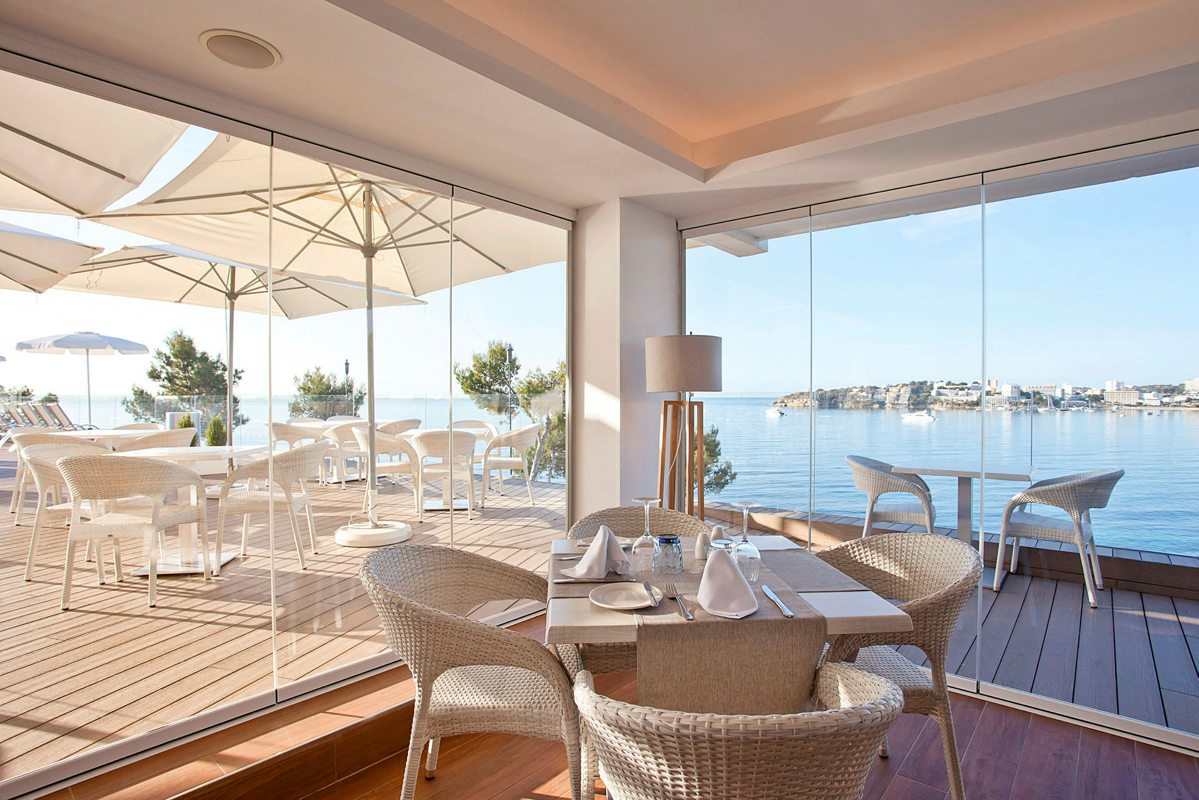 Bild av en restaurang med glasväggar och utsikt över en havsvik. (AI-genererad text)
