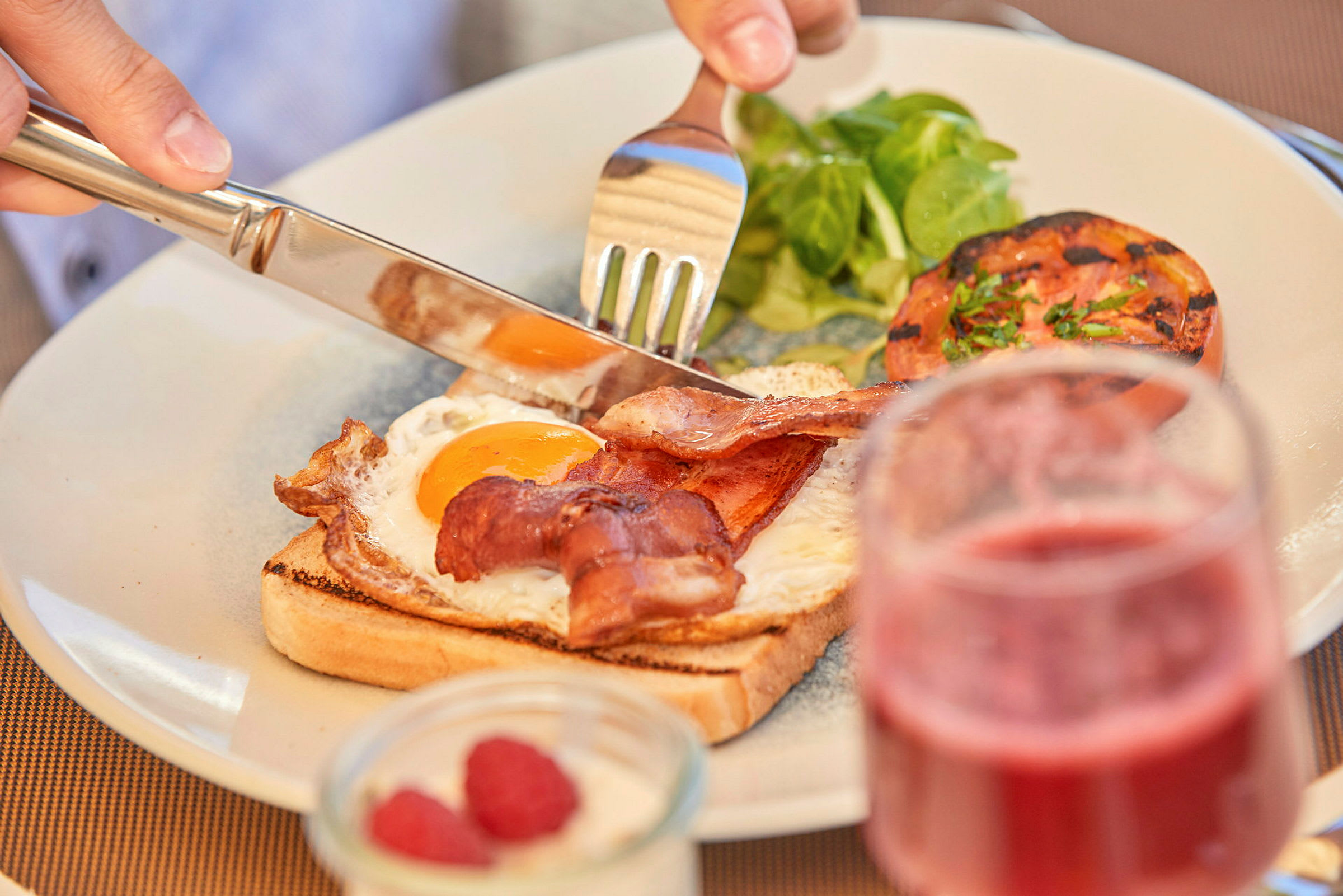 Tallerken med bacon, stekt egg og grønt. (AI-genererad text)