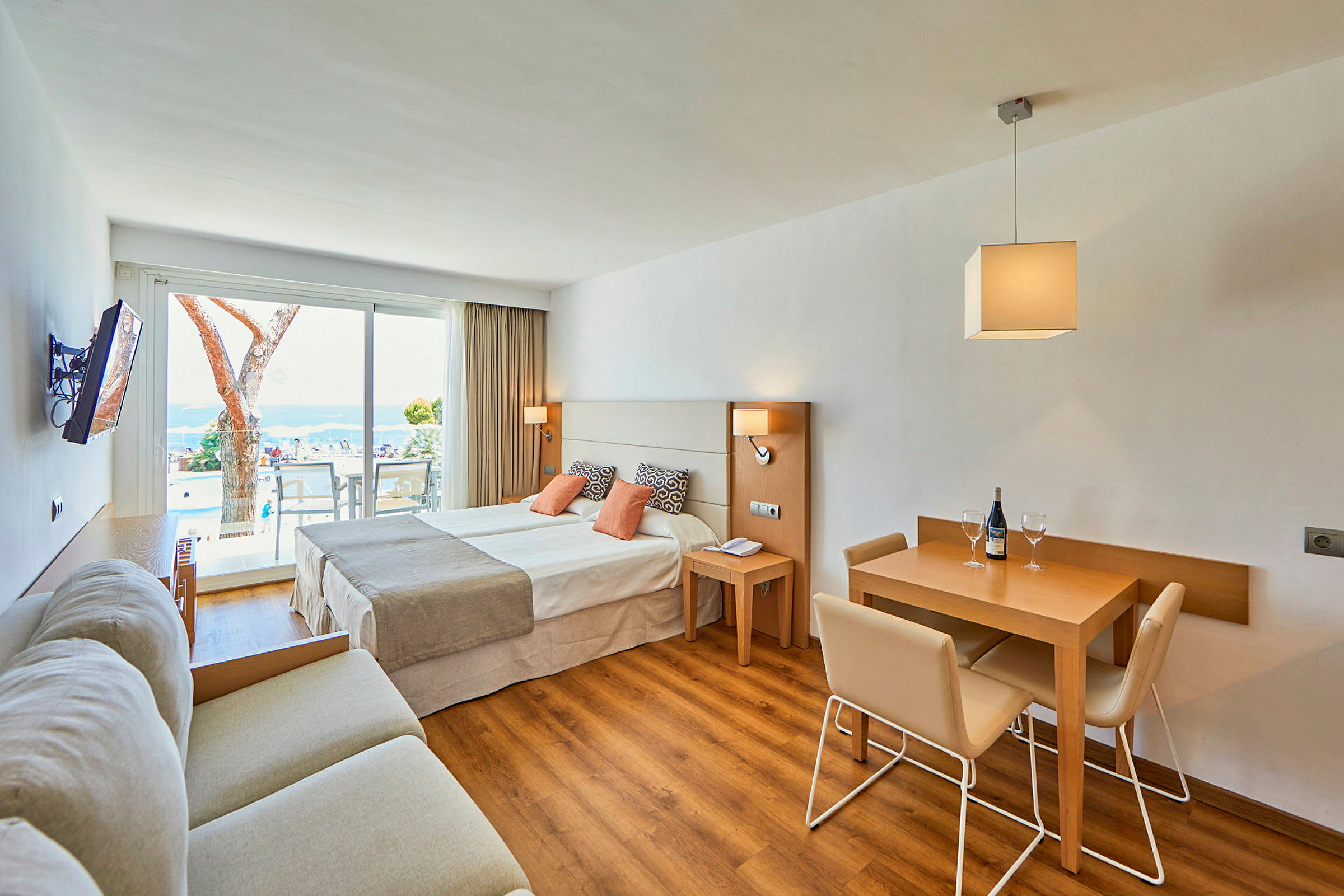 Hotelrum med dubbelsäng, sittgrupp och matbord med stolar. (AI-genererad text)
