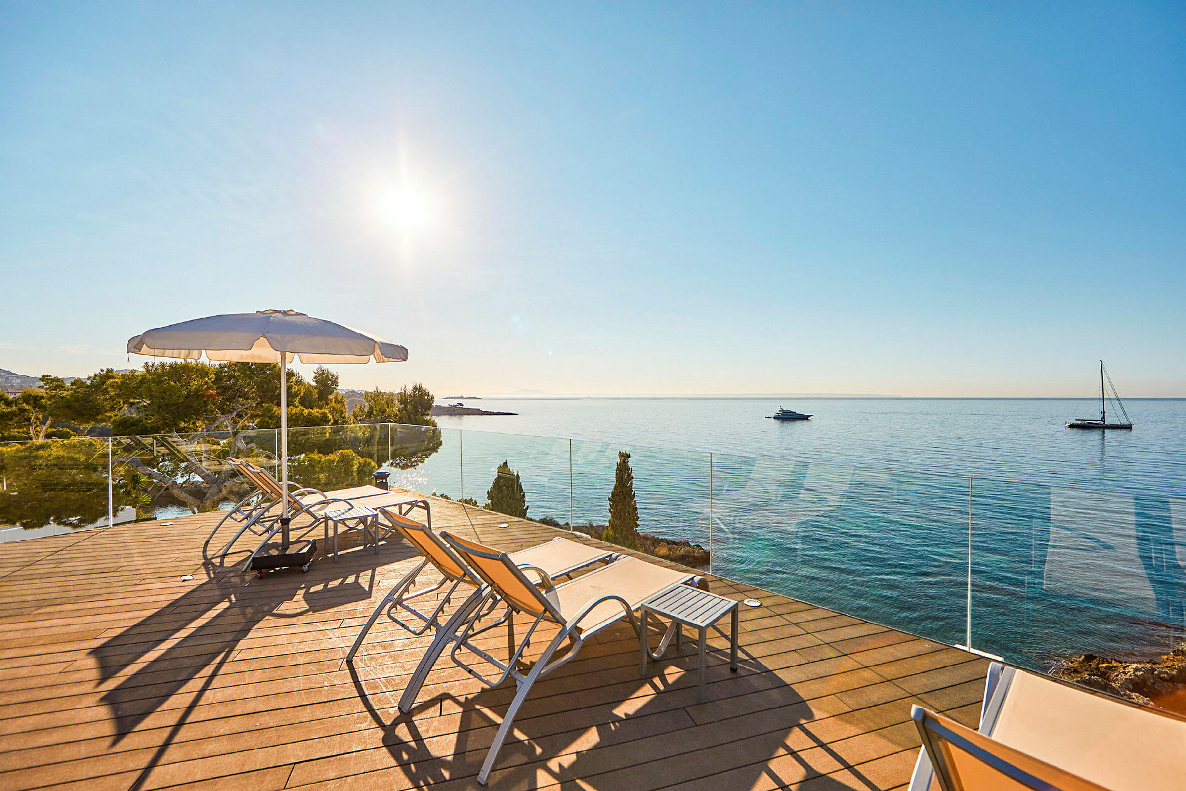 Solstolar och parasoll på en terrass med utsikt över havet. (AI-genererad text)
