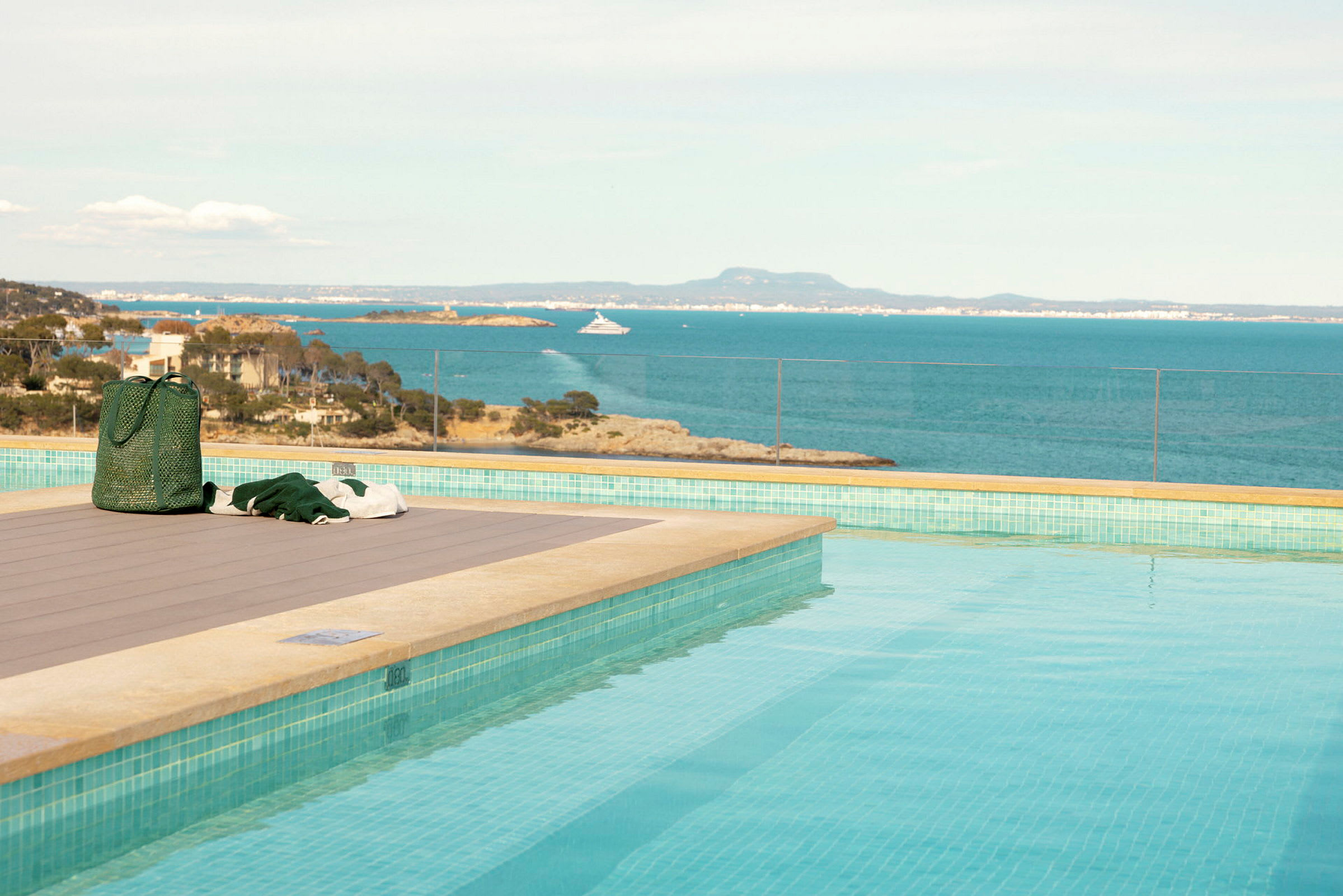 En pool med utsikt över havet och en klippa på en ö i bakgrunden. (AI-genererad text)