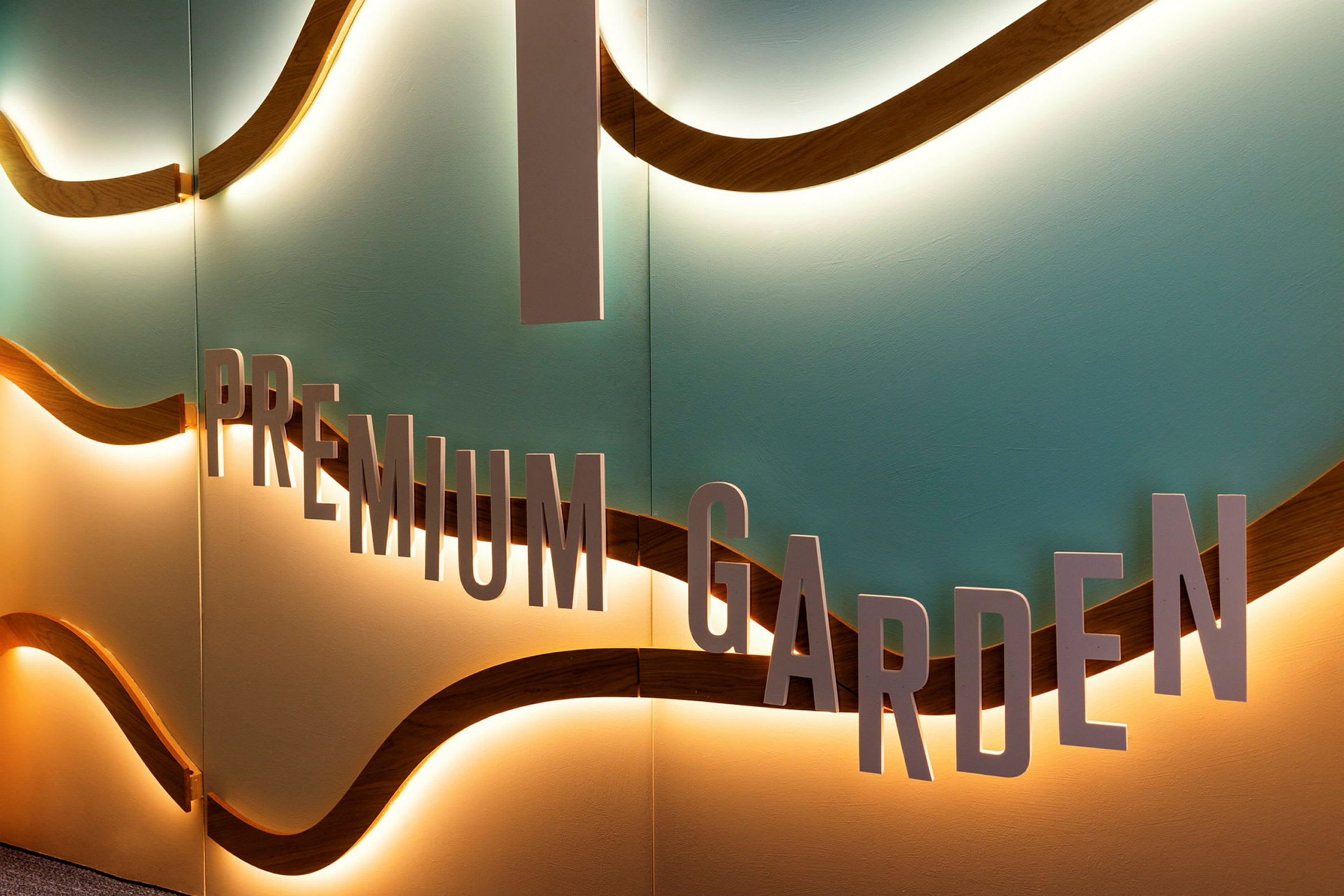 En vägg med texten 'Premium Garden' och vågformade detaljer med belysning. (AI-genererad text)