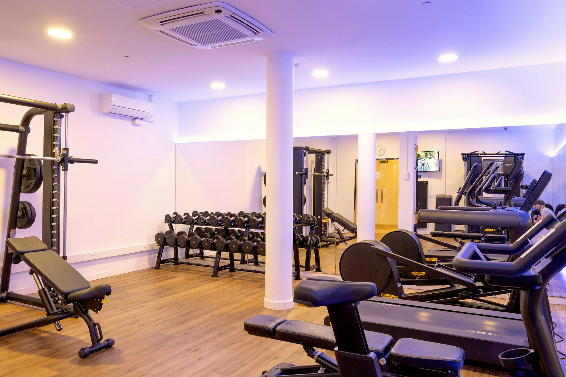 Ett gym med träningsutrustning såsom löpband, bänkpress och hantlar. (AI-genererad text)