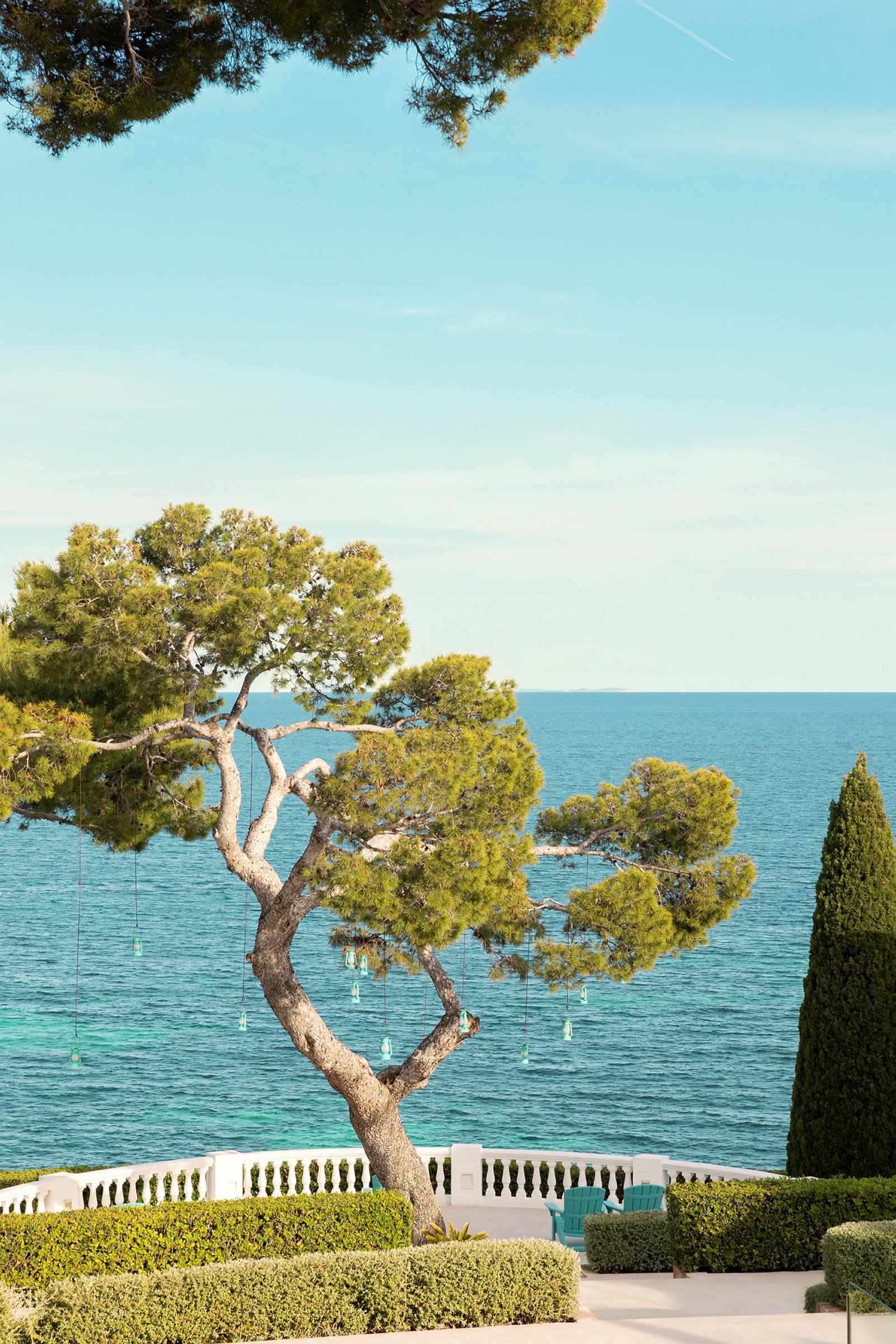 En utsikt över havet med ett träd i förgrunden och buskar vid en terrass. (AI-genererad text)