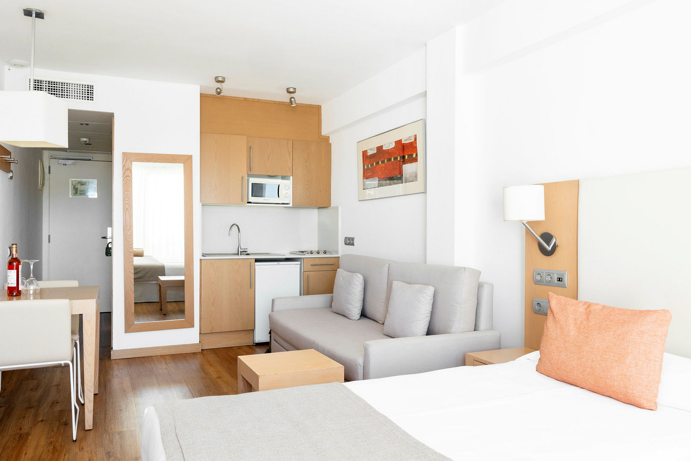 Ett ljust hotellrum med en bäddsoffa, ett pentry och ett matbord. (AI-genererad text)