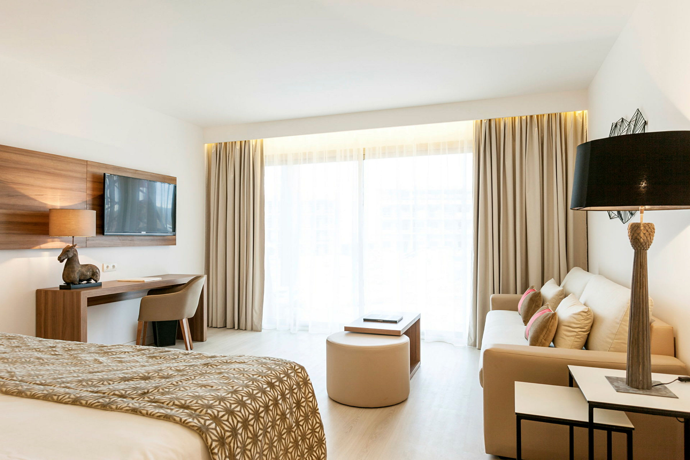 Bild av ett ljust hotellrum med bädd, soffa och skrivbord. (AI-genererad text)