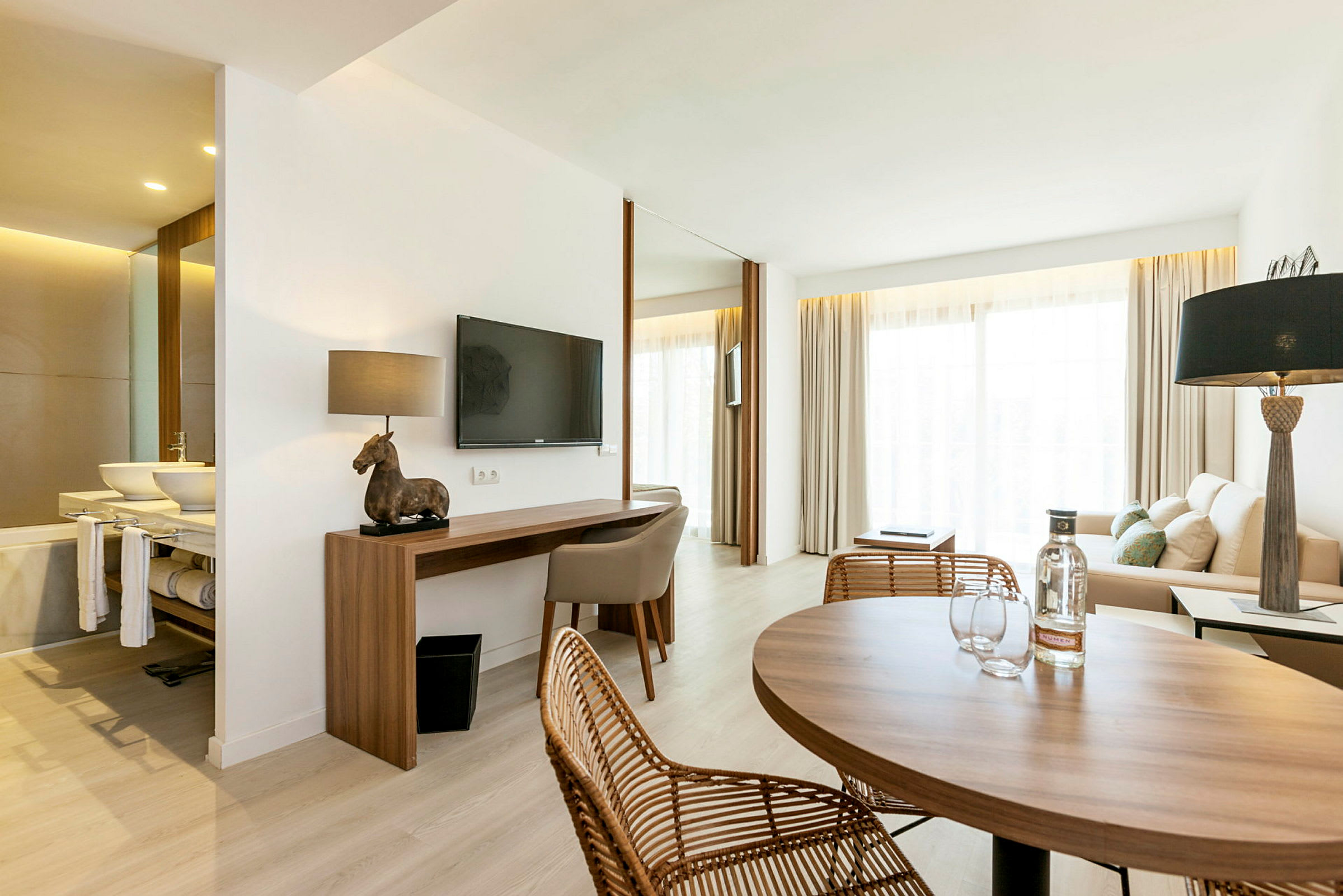 Ett modernt hotellrum med sittgrupp, ett skrivbord och ett bord. (AI-genererad text)