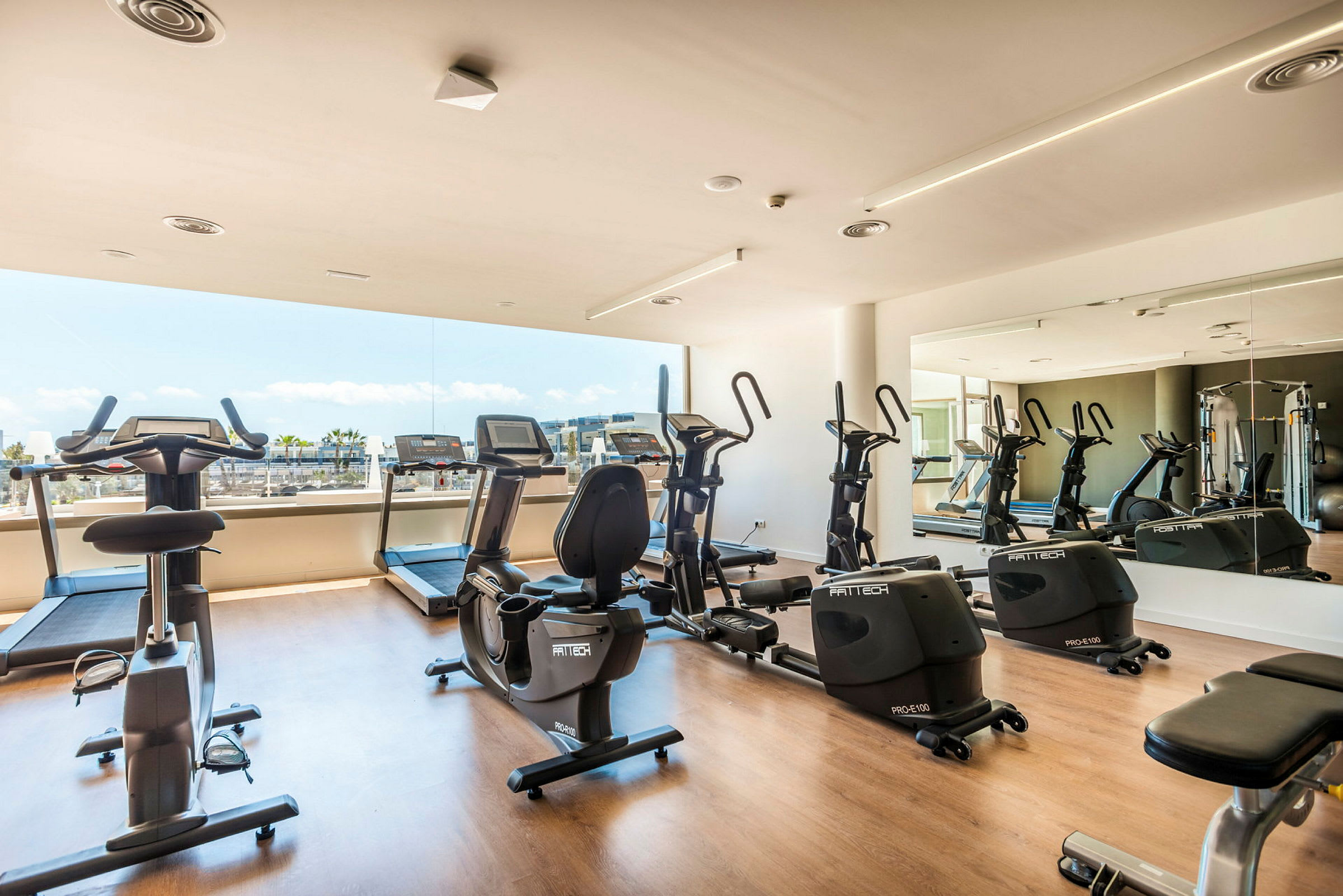 Ett gym med träningsmaskiner vid en stor fönsterruta. (AI-genererad text)