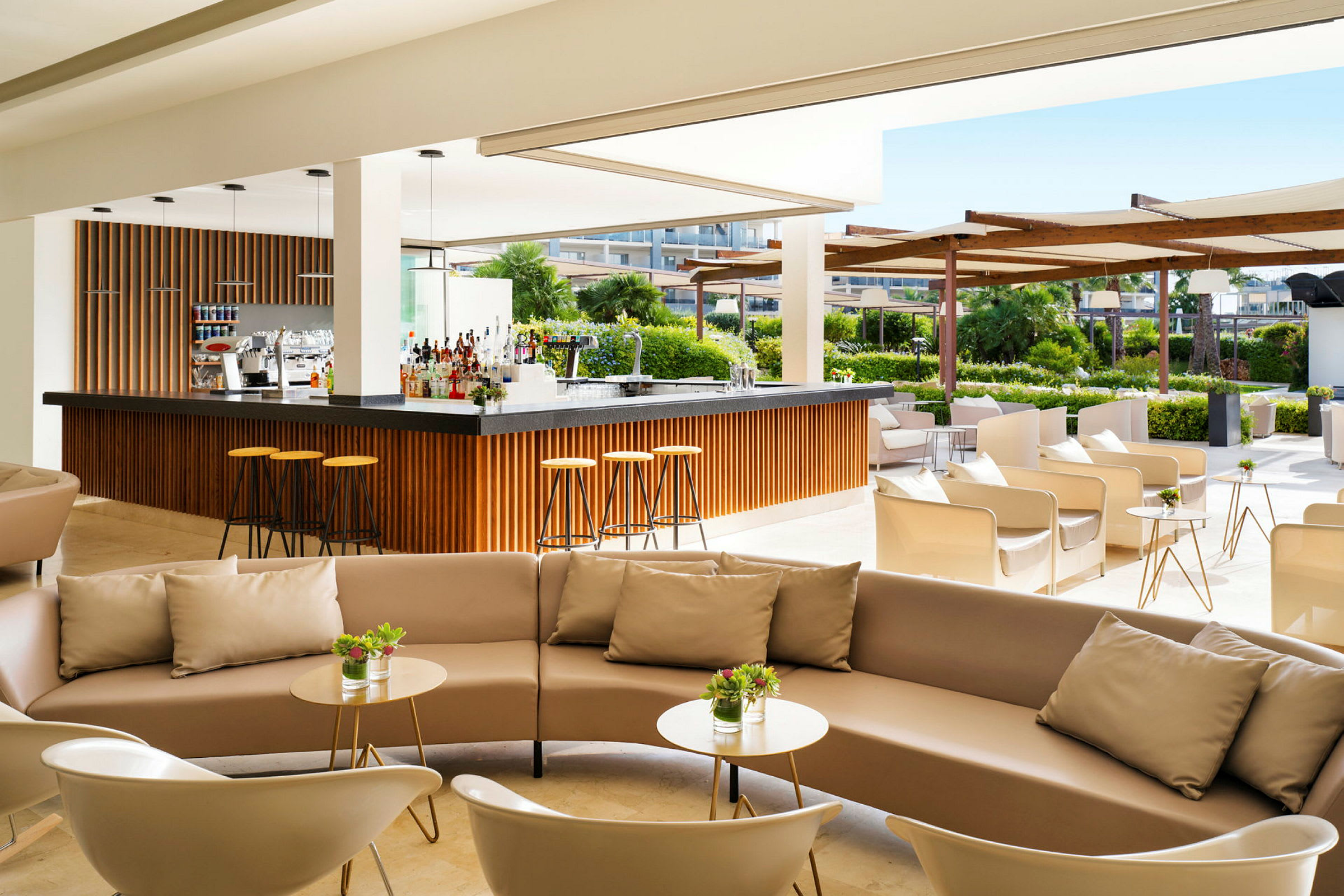 Modern bar utomhus med bekväma sittgrupper och grönska i bakgrunden. (AI-genererad text)