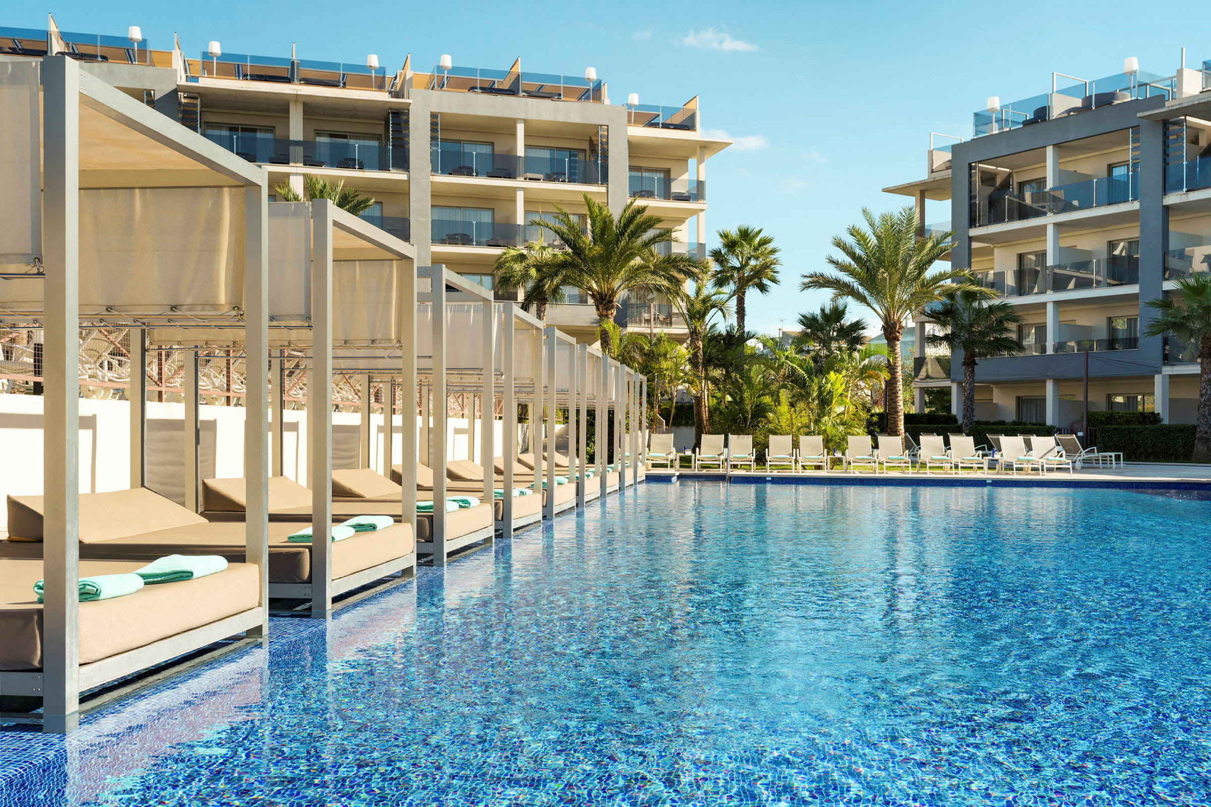 Utemiljö med pool, solstolar och hotellbyggnader. (AI-genererad text)