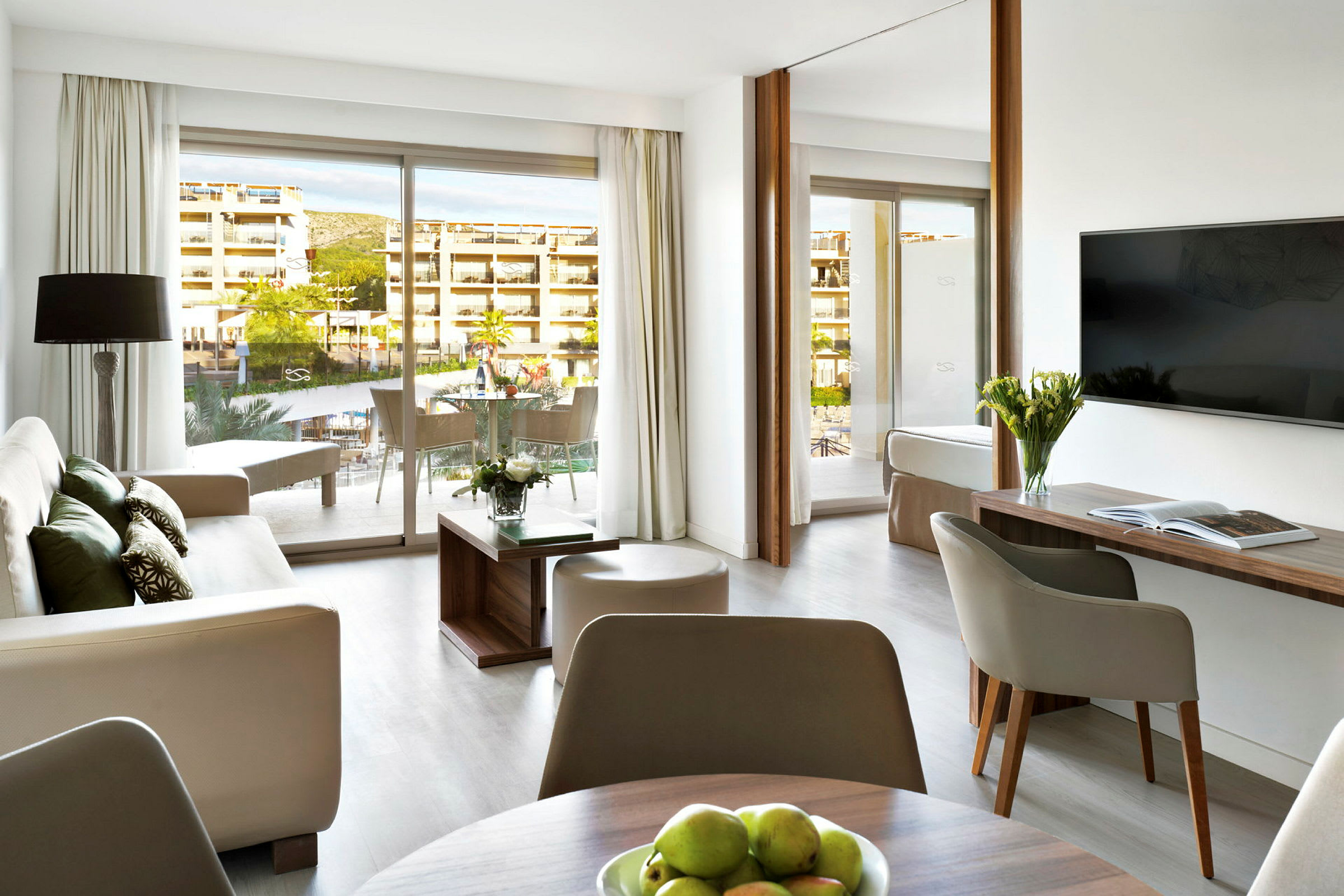 Modernt inredd hotellsvit med sittgrupp, bord, och balkong. (AI-genererad text)