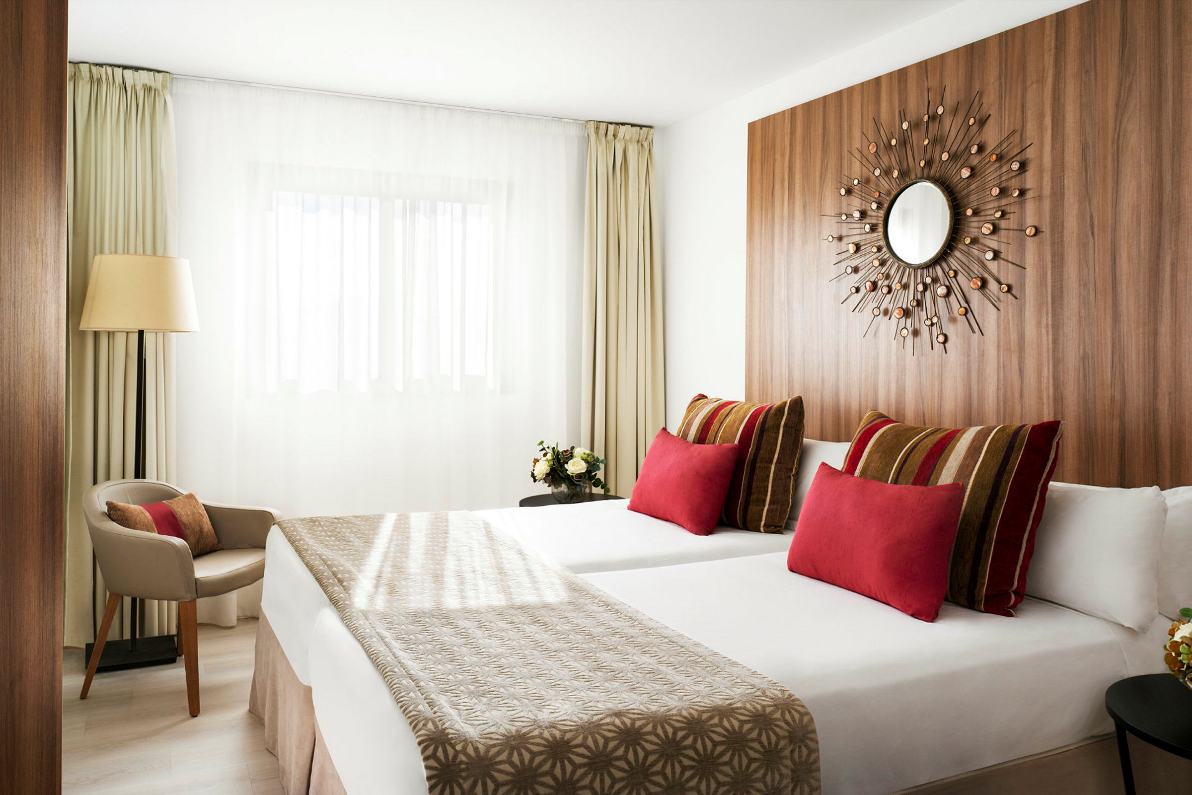 Modern hotellrum med två sängar, färgstarka kuddar och minimalistisk inredning. (AI-genererad text)