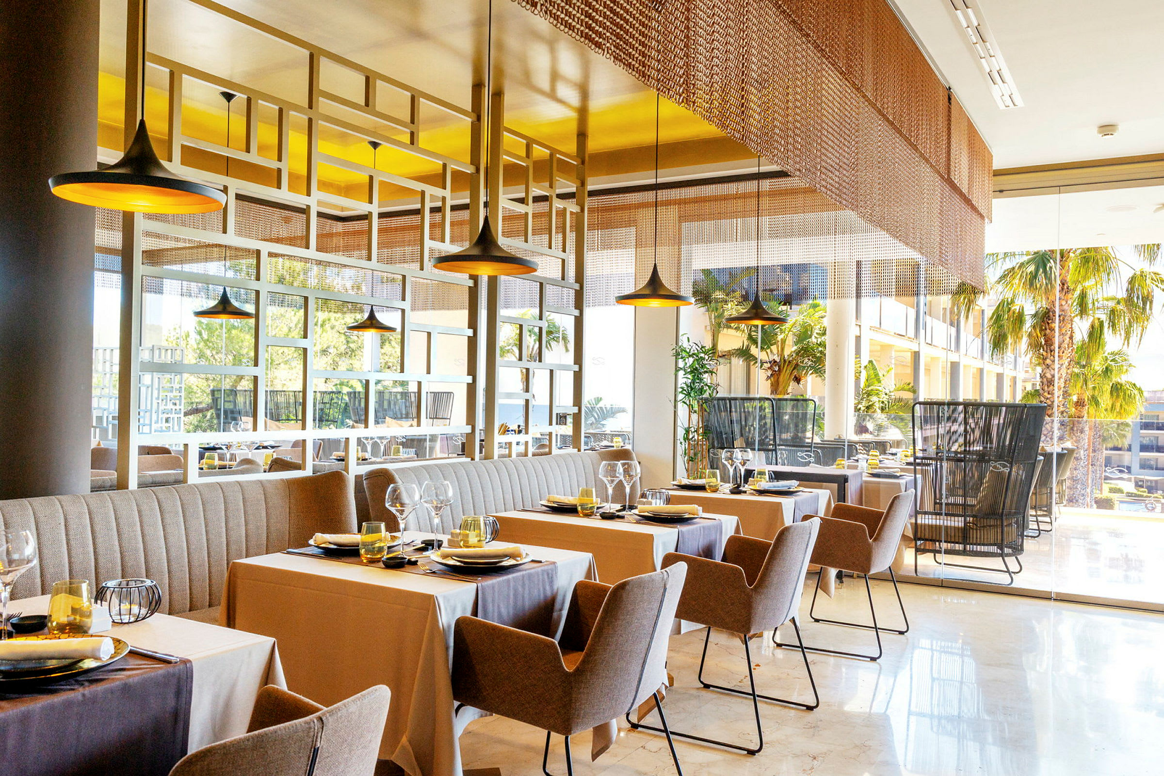 Bild av en modern restaurang med uppdukade bord och stolar, stora fönster samt inredning i behagliga färger. (AI-genererad text)
