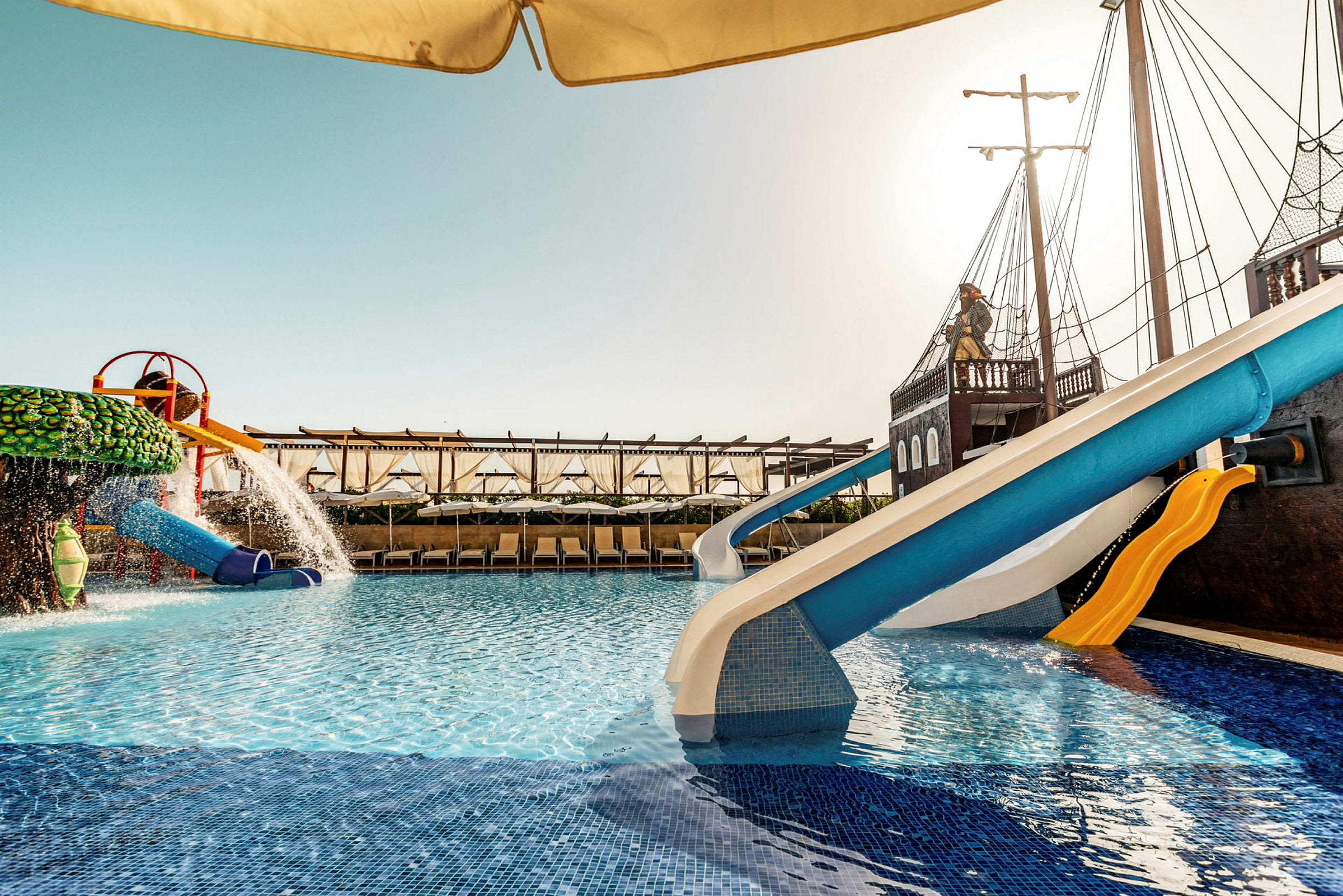 En swimmingpool med vattenrutschbanor och en temadekoration som liknar ett piratskepp. (AI-genererad text)