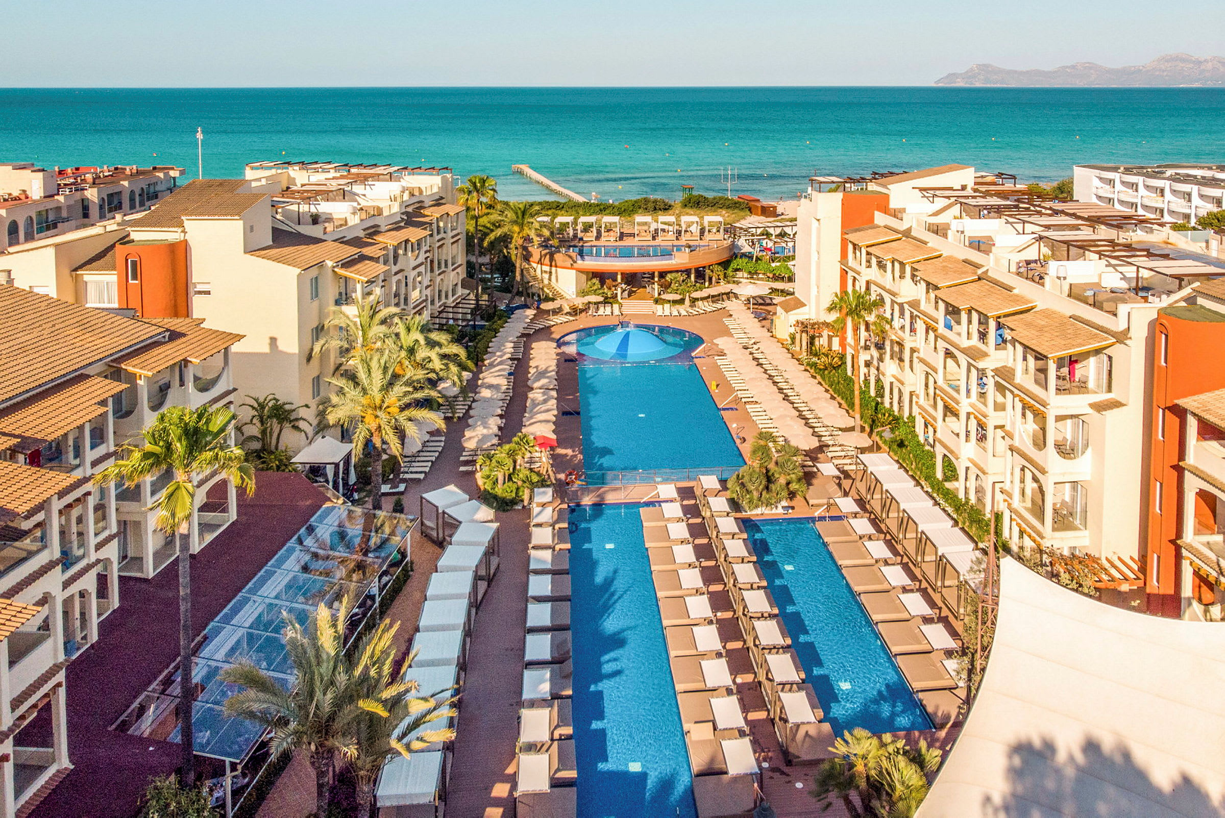 Utsikt över en resort med pooler och havet i bakgrunden. (AI-genererad text)