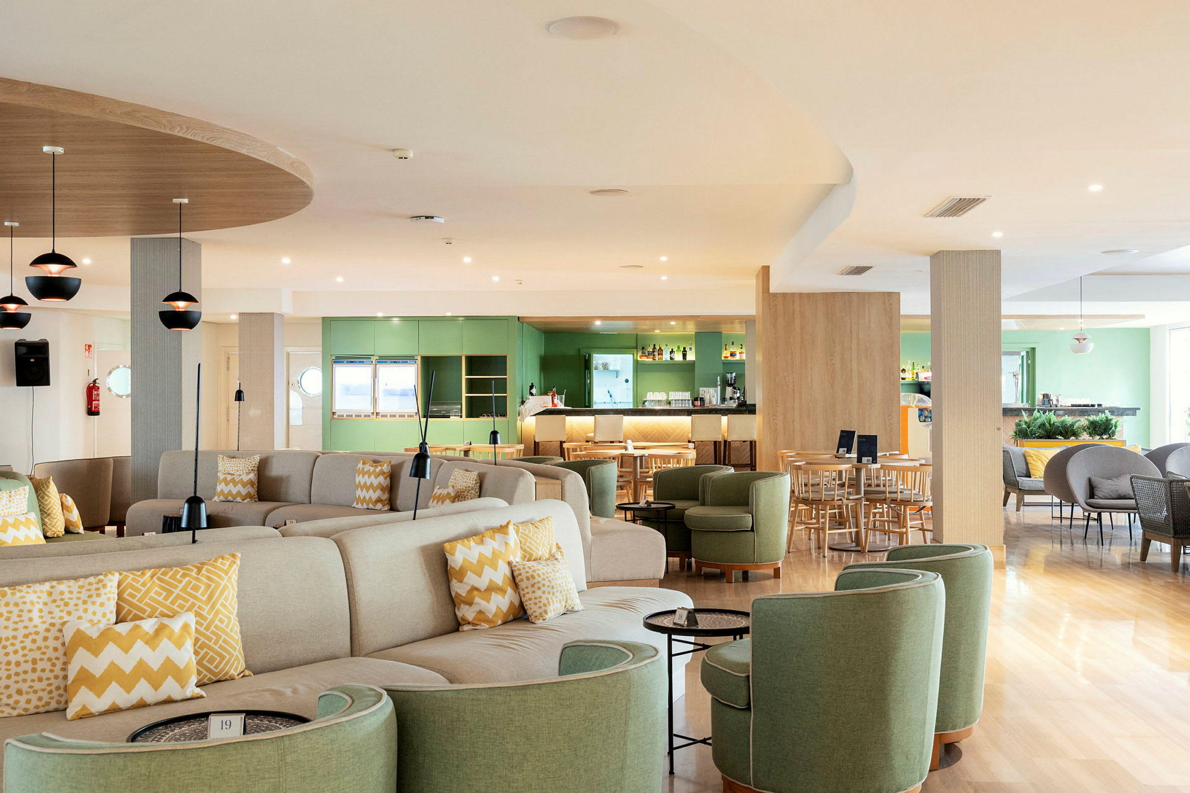 Restaurang med sittgrupper och barområde, ljusa färger och modern inredning. (AI-genererad text)
