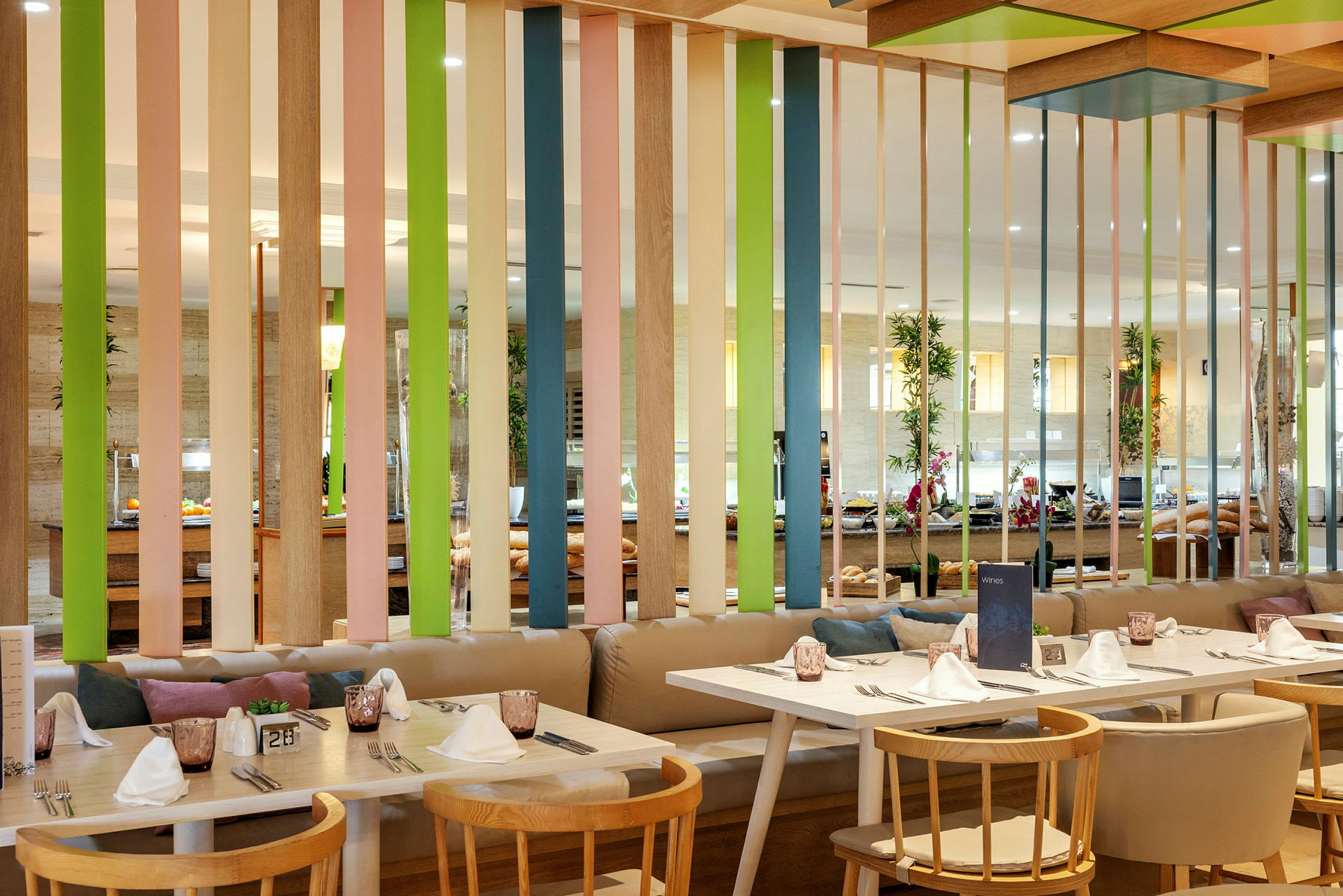 Interiör av en restaurang med bord, stolar och en färgglad avskärmning. (AI-genererad text)