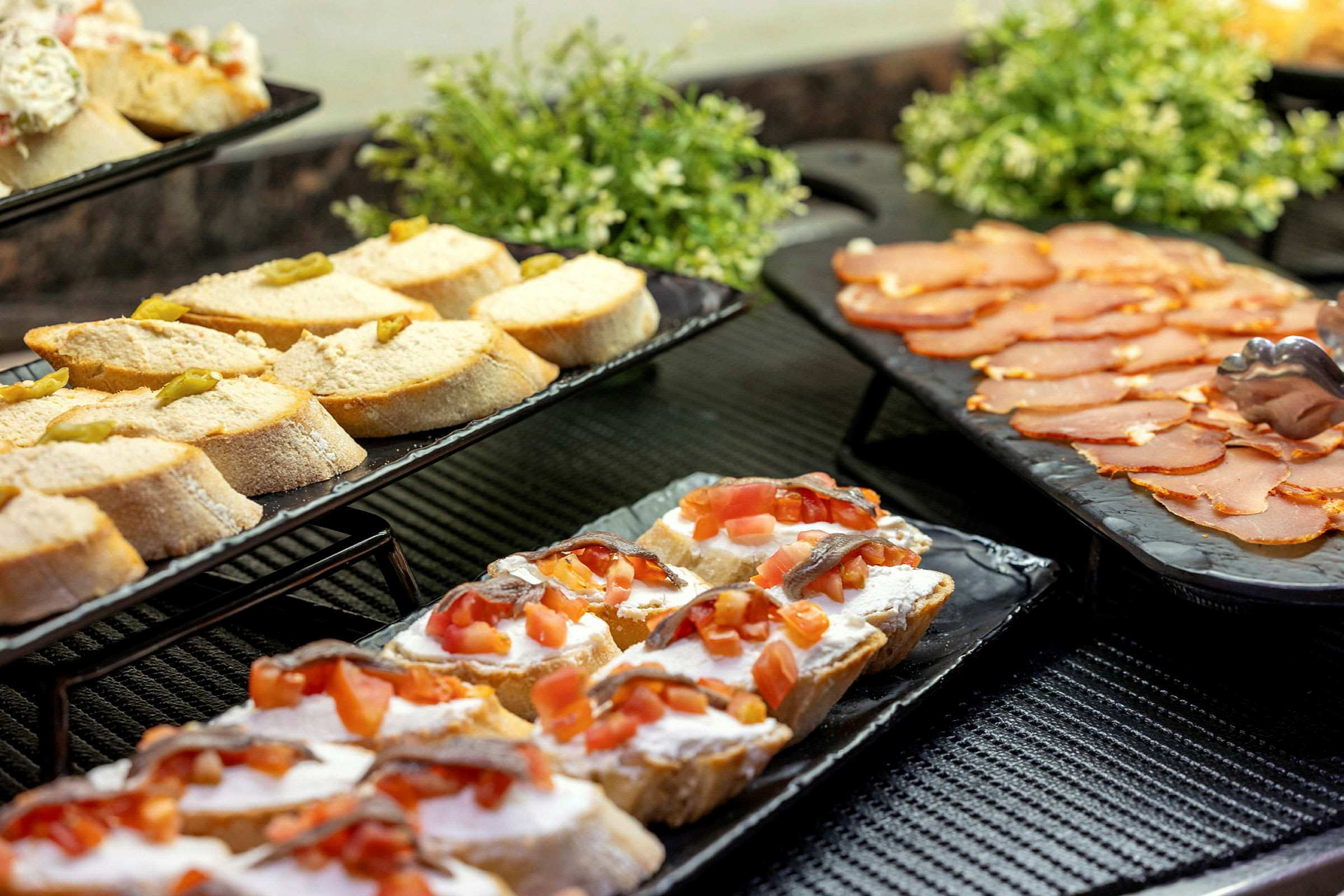 Smörgåsar upplagda på fat tillsammans med pålägg på ett bord. (AI-genererad text)