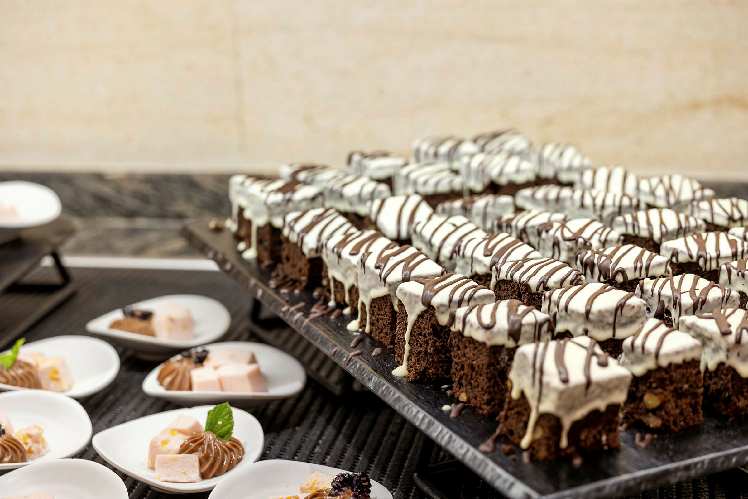En buffé med chokladkakor dekorerade med vit och mörk glasyr på ett serveringsbord. (AI-genererad text)