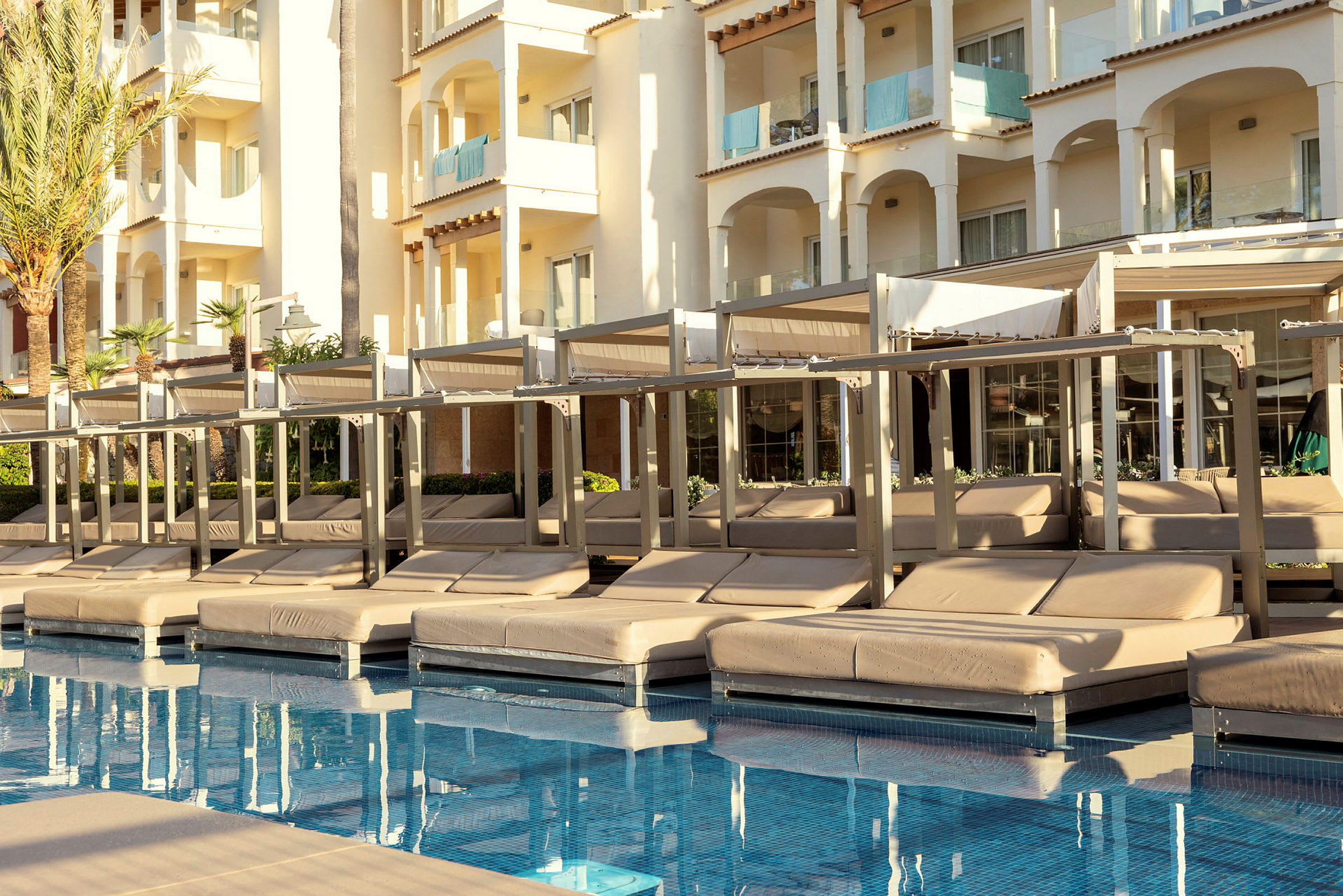 Solbäddar vid en pool med en hotellbyggnad i bakgrunden. (AI-genererad text)