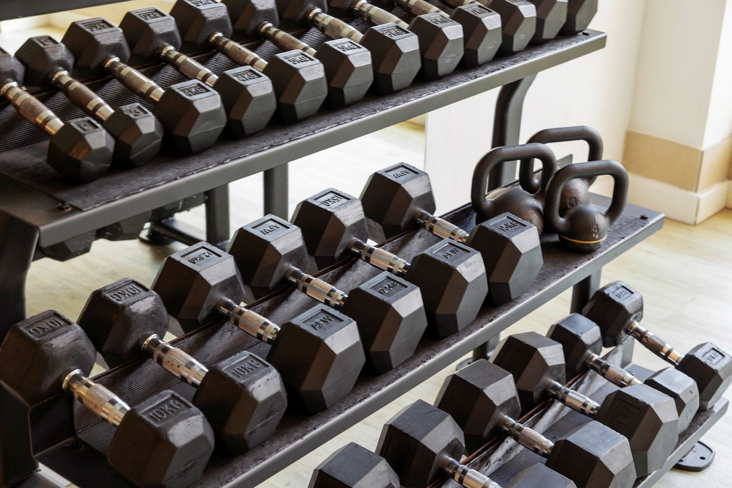 Ett ställ med vikthantlar och kettlebells i svart metall. (AI-genererad text)