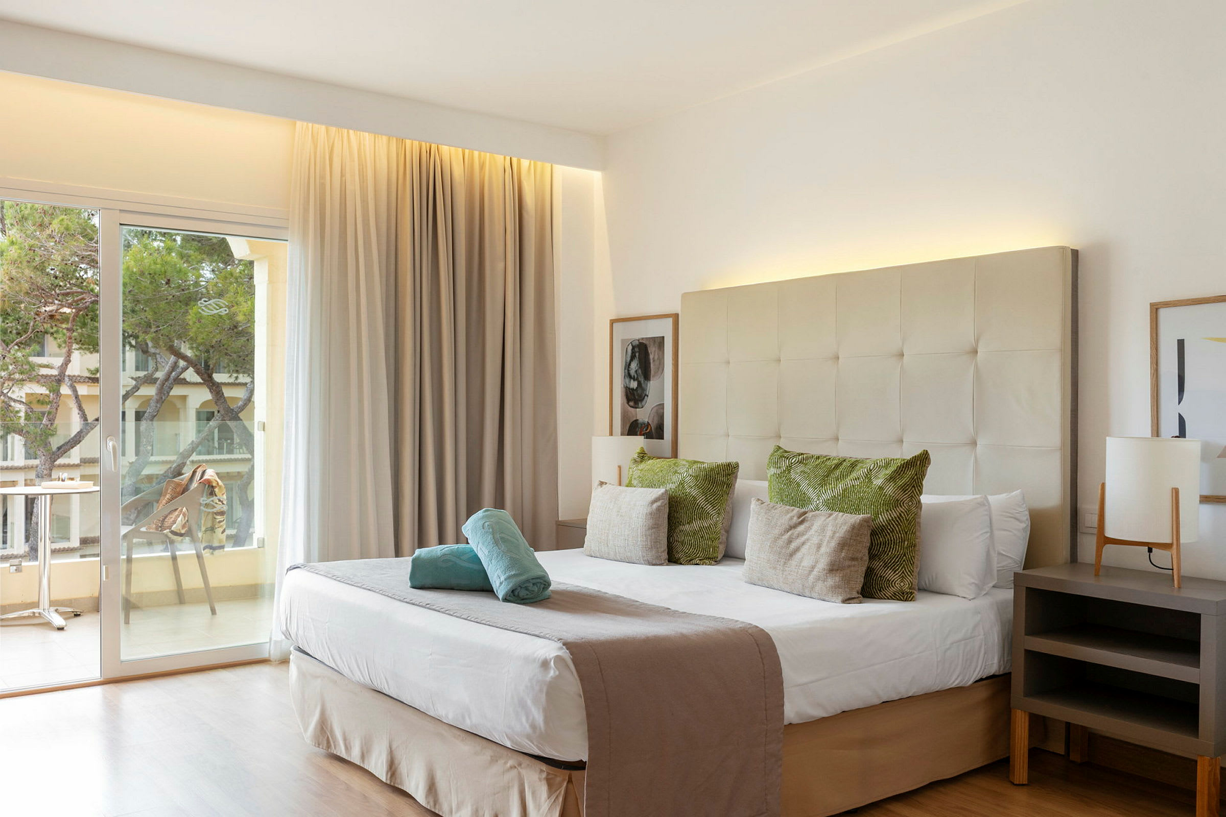 Hotelrum med dubbelsäng, inredning i neutrala färger och en balkong med utsikt. (AI-genererad text)