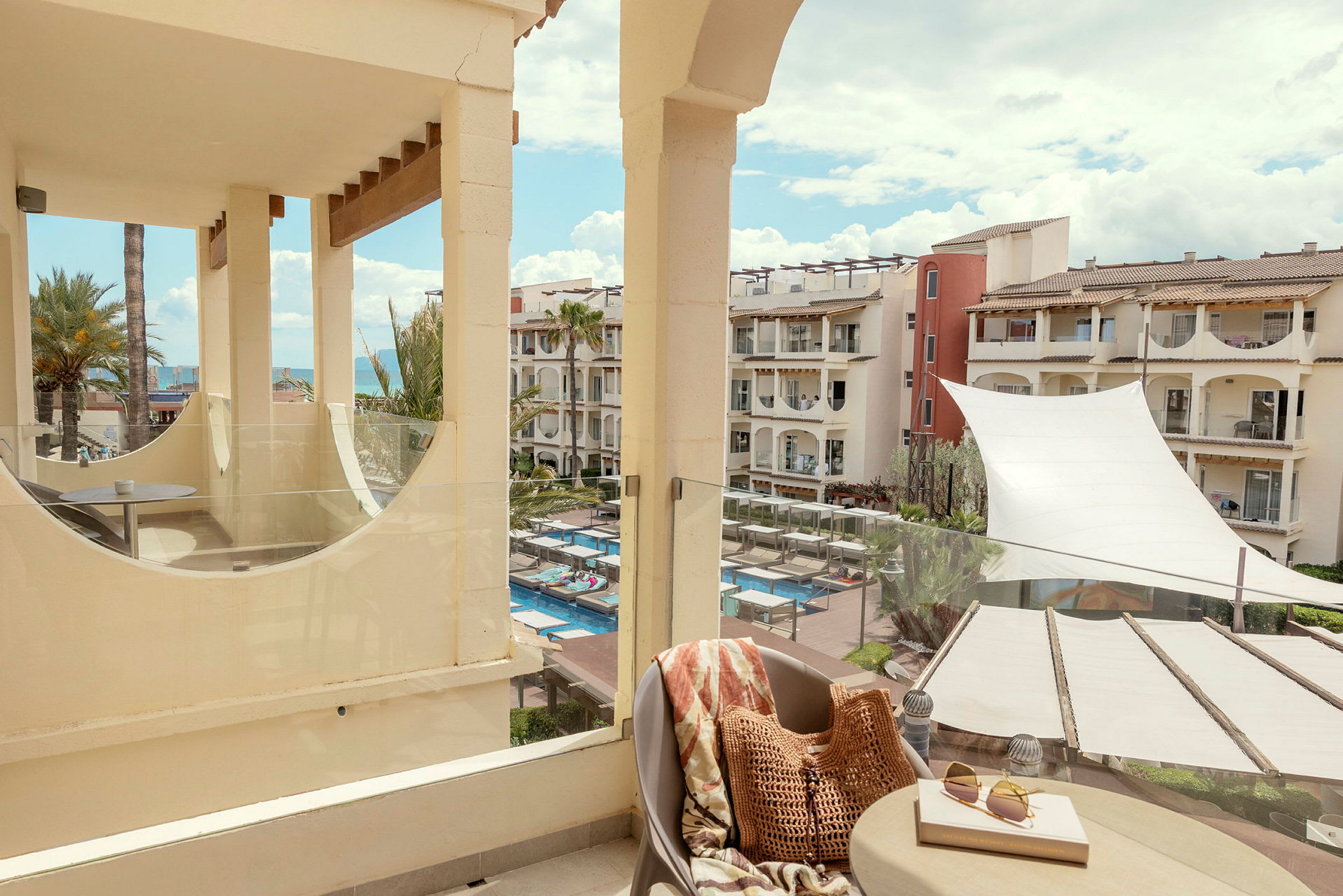 En balkong med utsikt över en hotellpool och omgivande byggnader. (AI-genererad text)