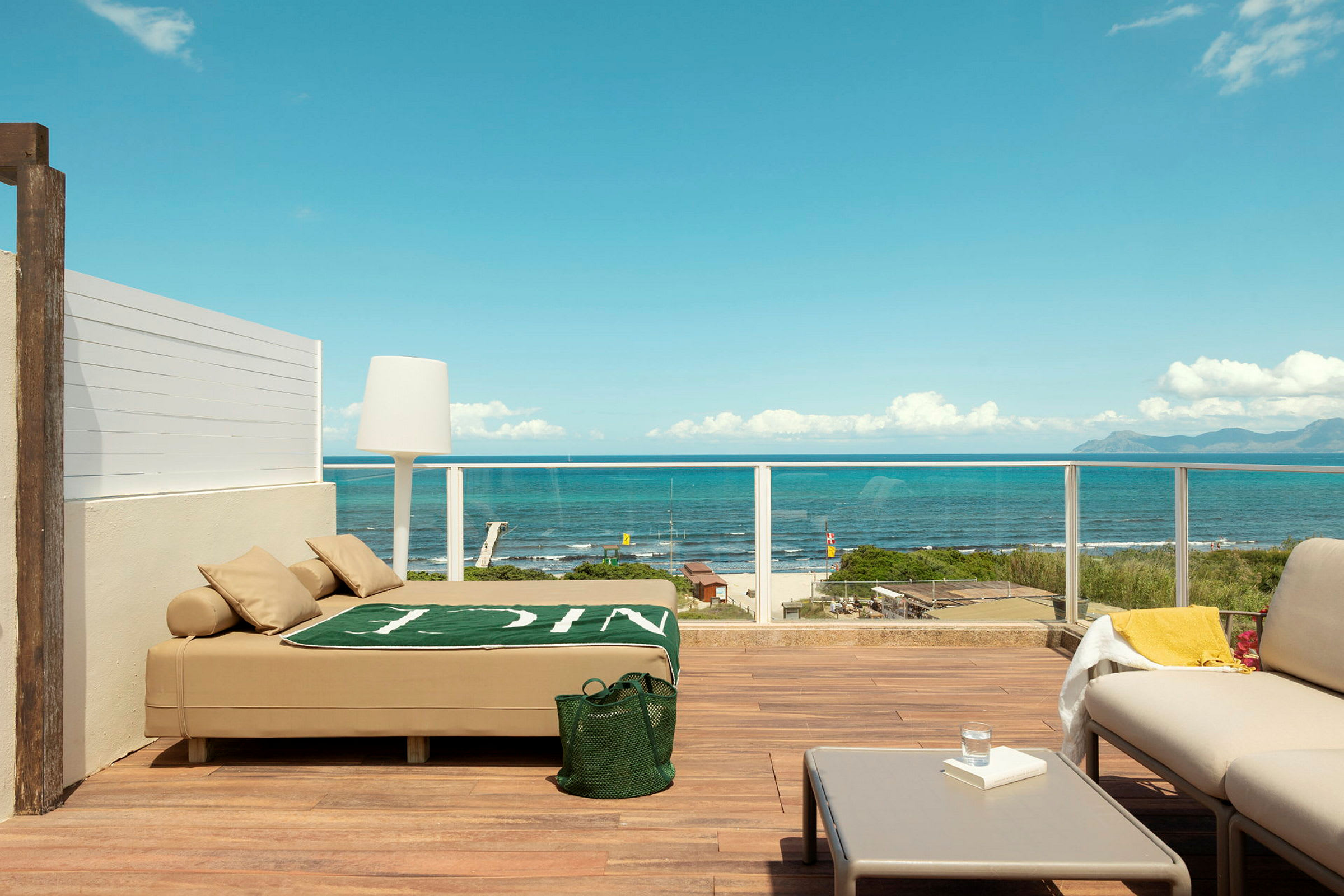 Terrass med modern möblering och utsikt över havet, inklusive en solbädd, soffmöbler och bord. (AI-genererad text)