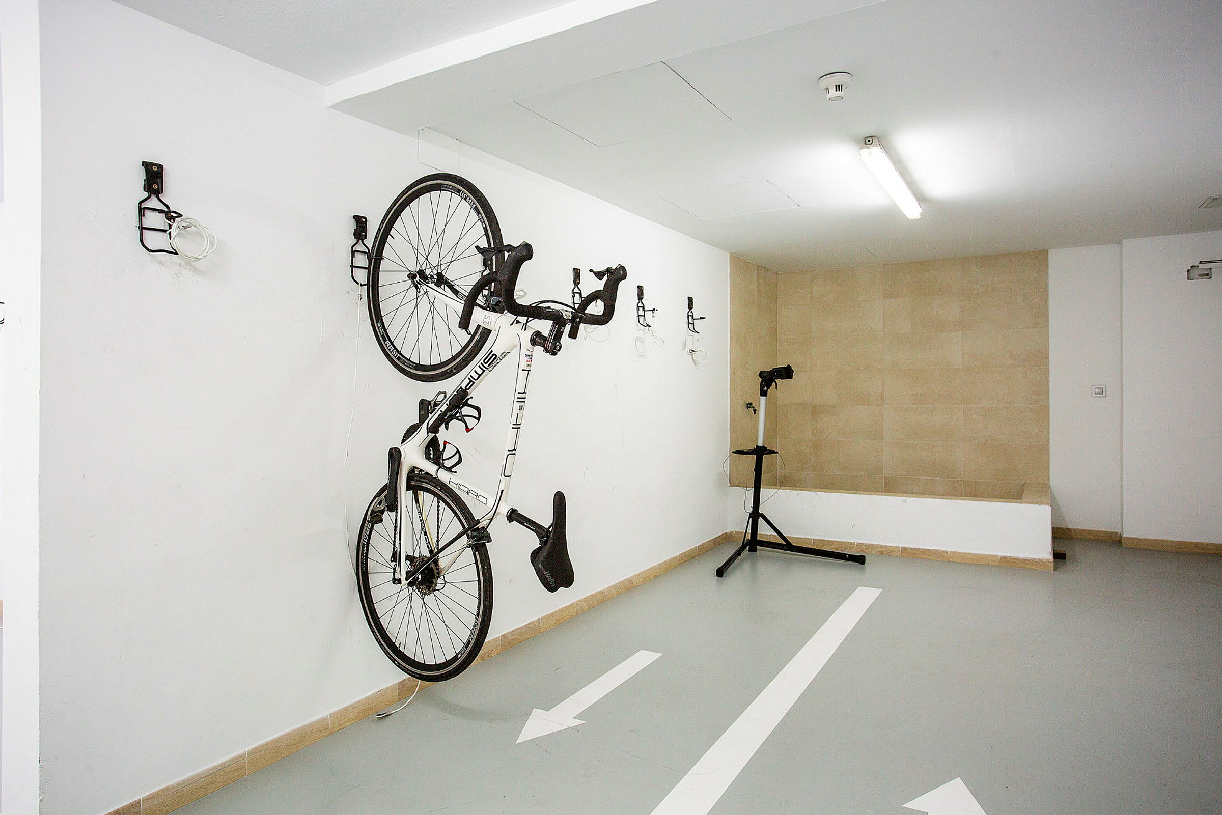 En cykel hänger på väggen i ett garage. Ett reparationsstativ står bredvid. (AI-genererad text)
