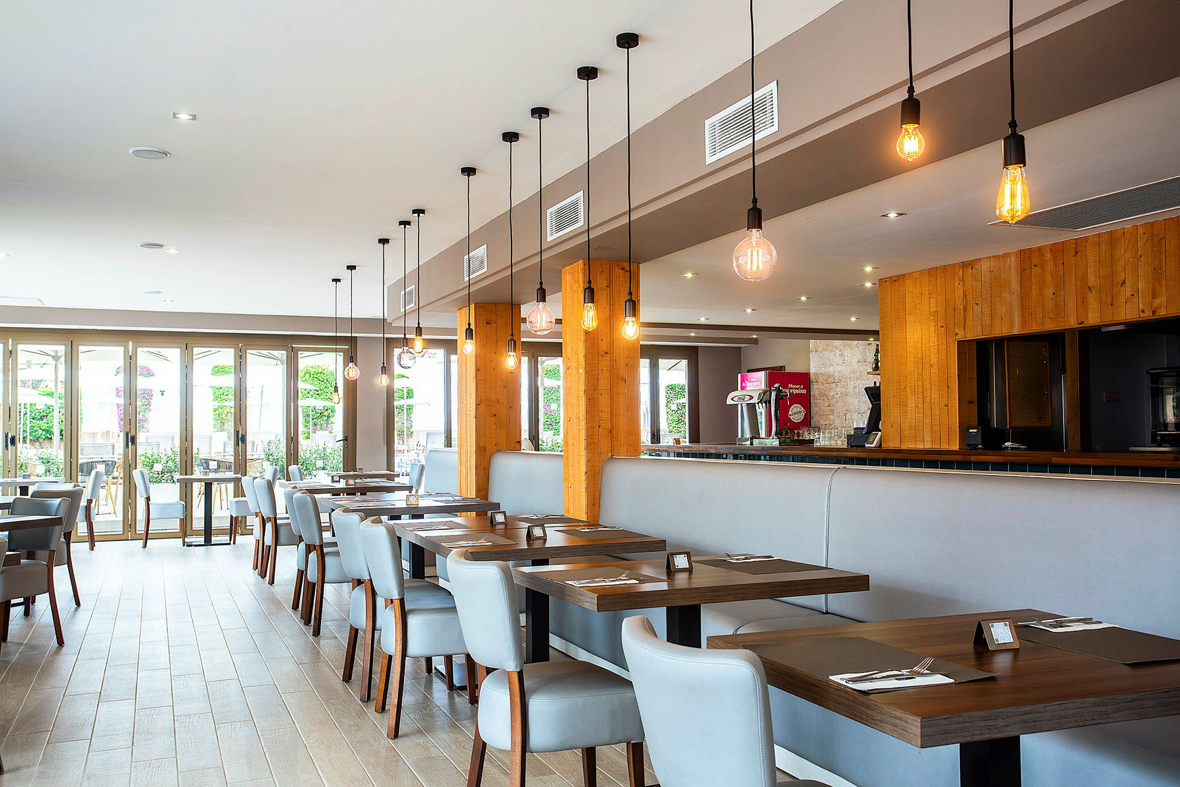 Moderna restaurangbord med stolar i ljus interiör och hängande lampor. (AI-genererad text)
