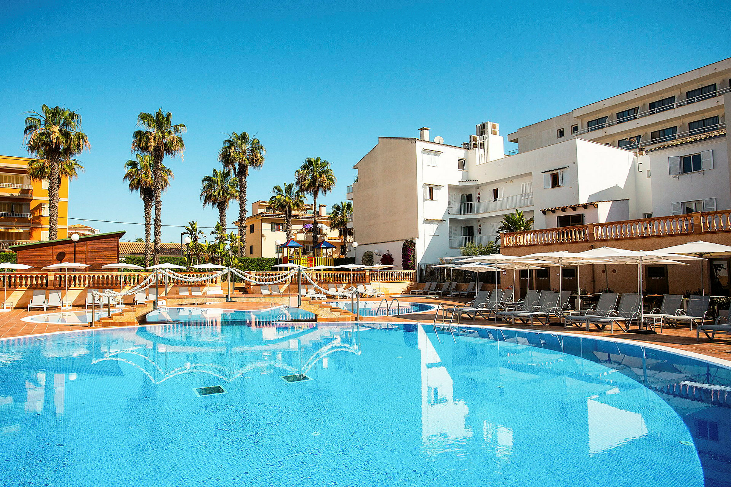 Utomhuspool med solstolar och parasoller vid ett hotellområde. (AI-genererad text)