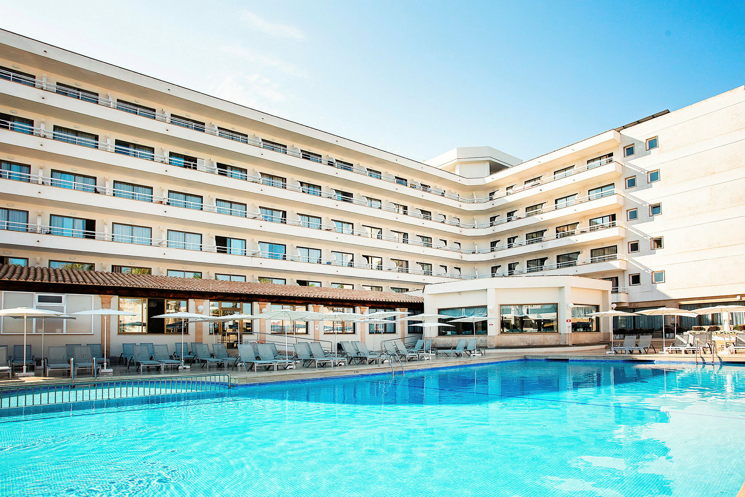 En bild av ett hotell med flera våningar och en pool framför byggnaden. (AI-genererad text)