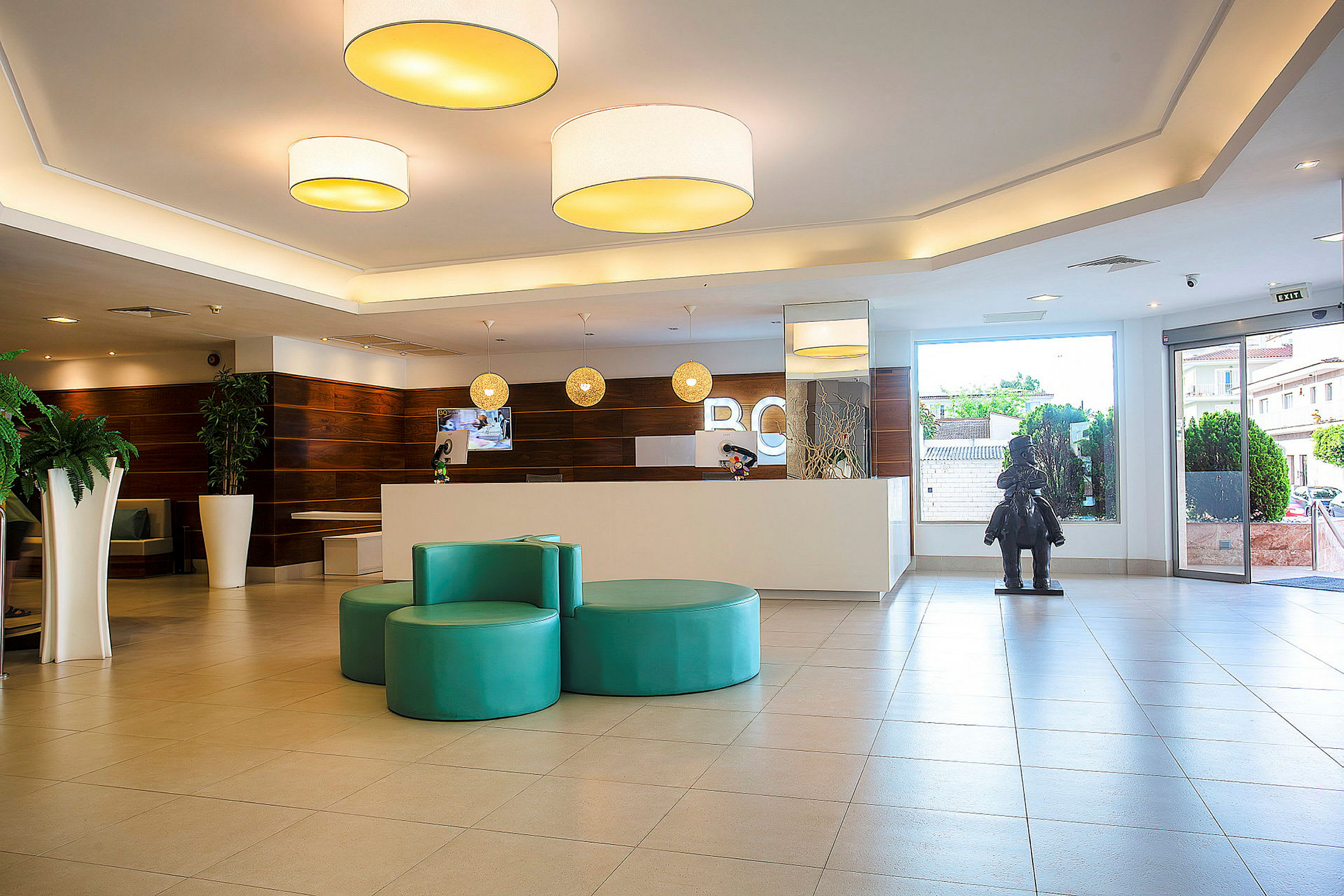 Hotellobby med reception, sittmöbler och en fönsterdörr. (AI-genererad text)