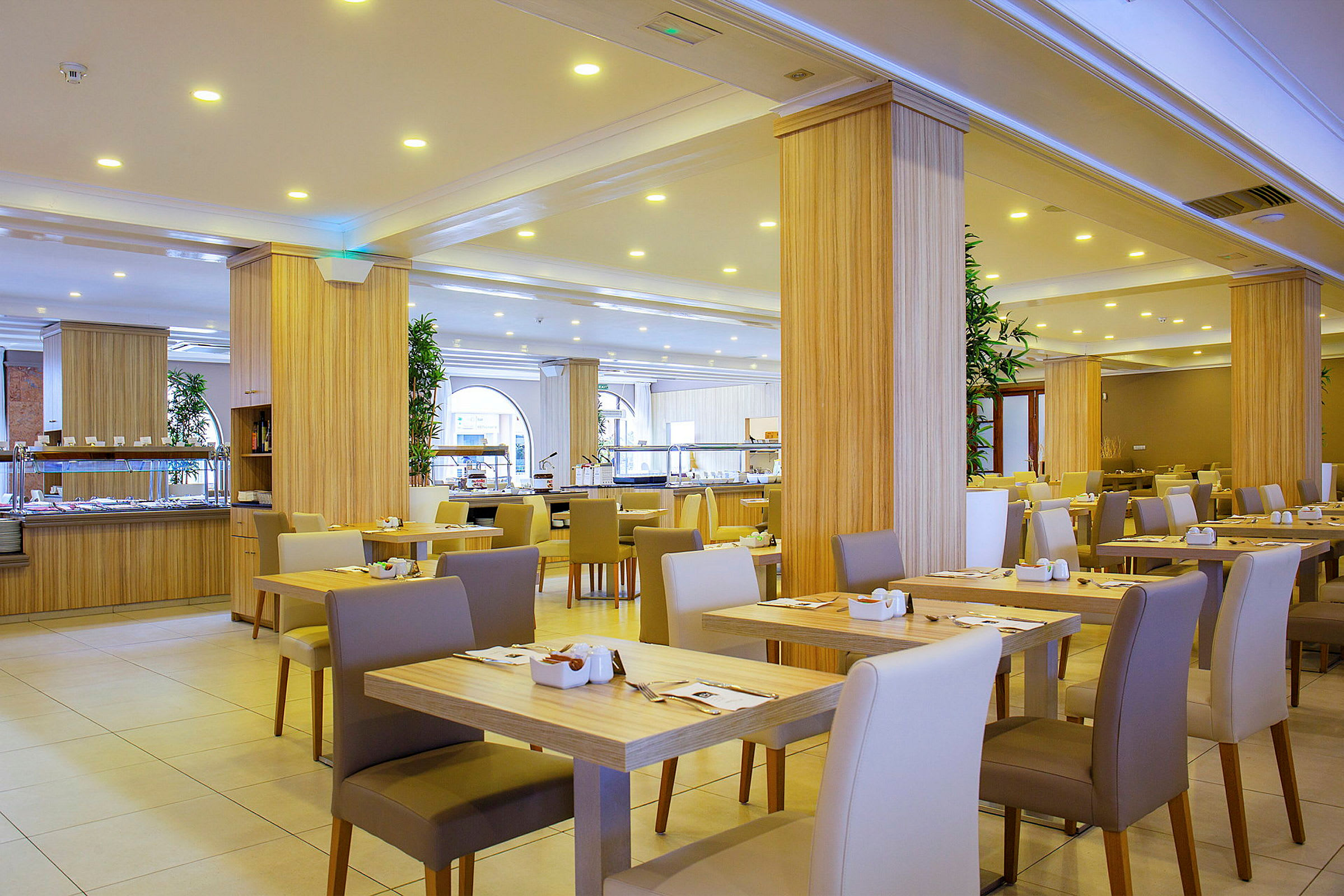 En modern restaurang med ljus inredning och dukade bord. (AI-genererad text)