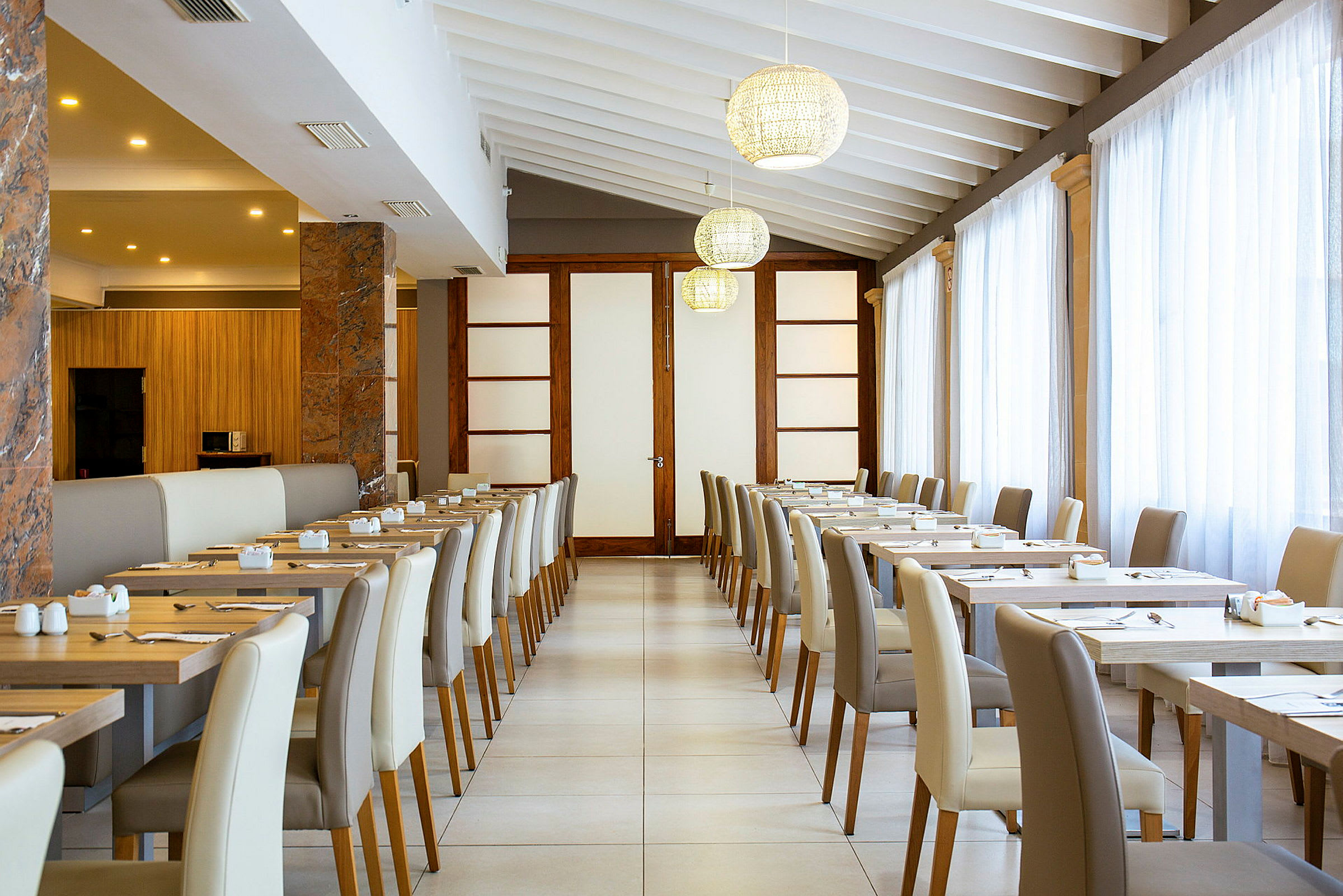 Inredning av en ljus restaurang med dukade bord och stolar. (AI-genererad text)