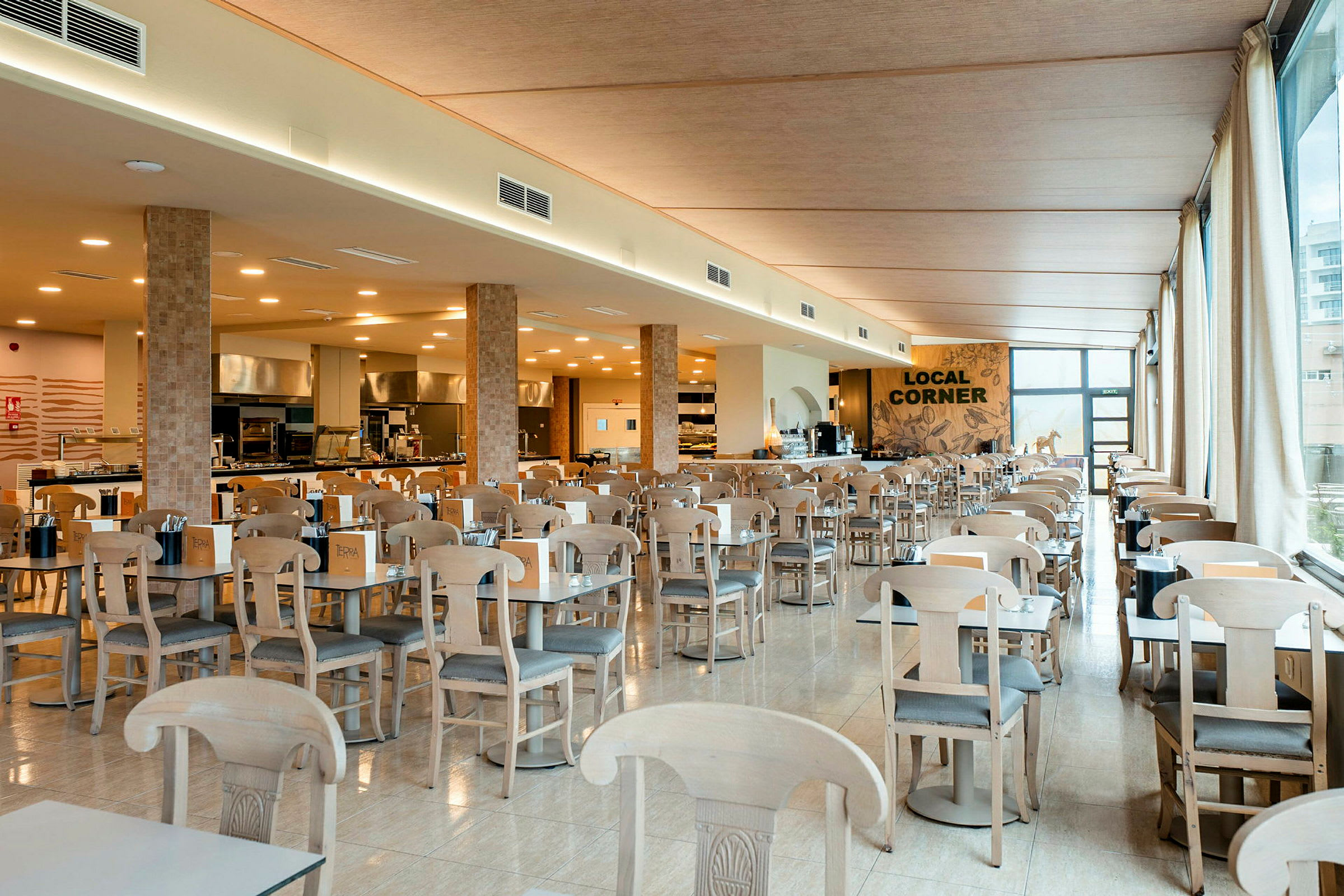 Interiör av en rymlig restaurang med många bord och stolar samt en serveringsdisk i bakgrunden. (AI-genererad text)