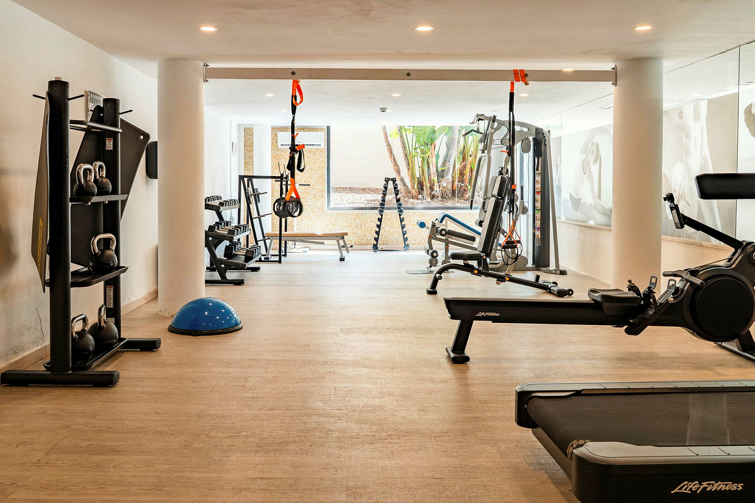 Bild av ett gym med olika träningsmaskiner såsom löpband, roddmaskin och gymutrustning. (AI-genererad text)