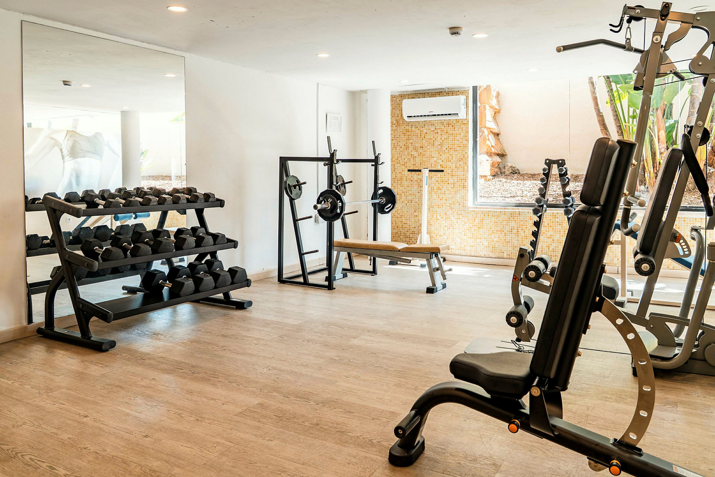 Ett gym med träningsutrustning som hantlar, träningsbänk och styrketräningsmaskiner. (AI-genererad text)
