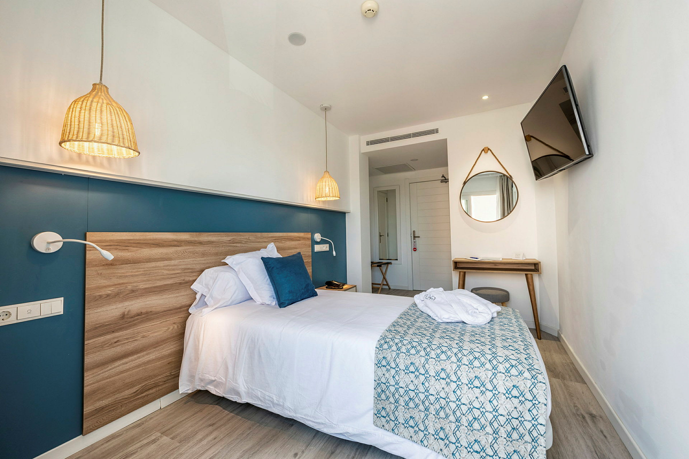 Modernt hotellrum med säng, spegel och TV. (AI-genererad text)