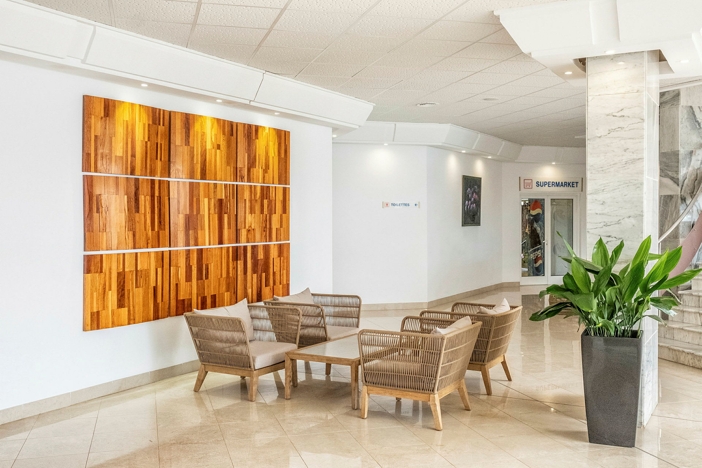 En lobby med sittgrupp, växt och träpanel på väggen. (AI-genererad text)
