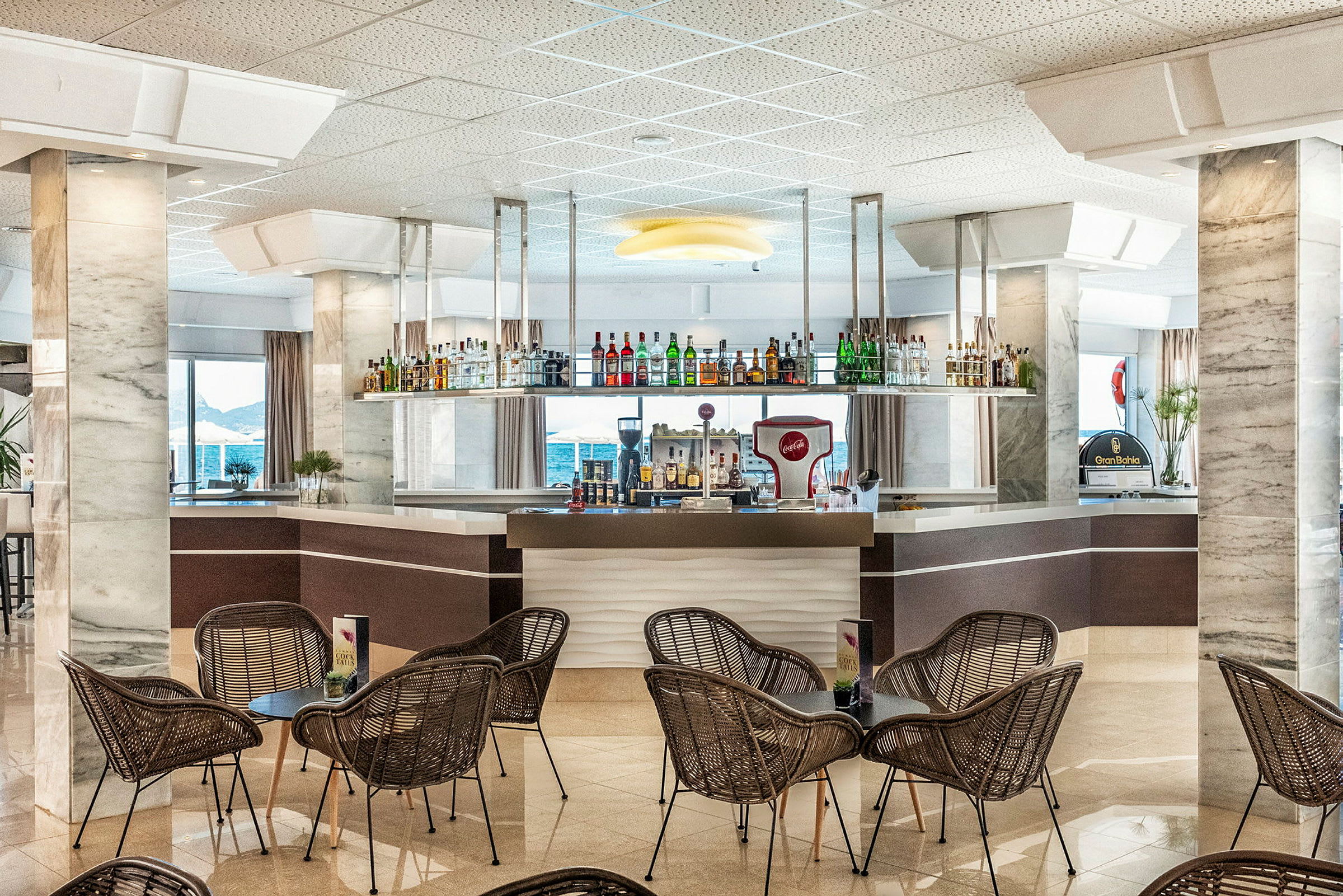 Hotellbar med stolar och bord i förgrunden. (AI-genererad text)