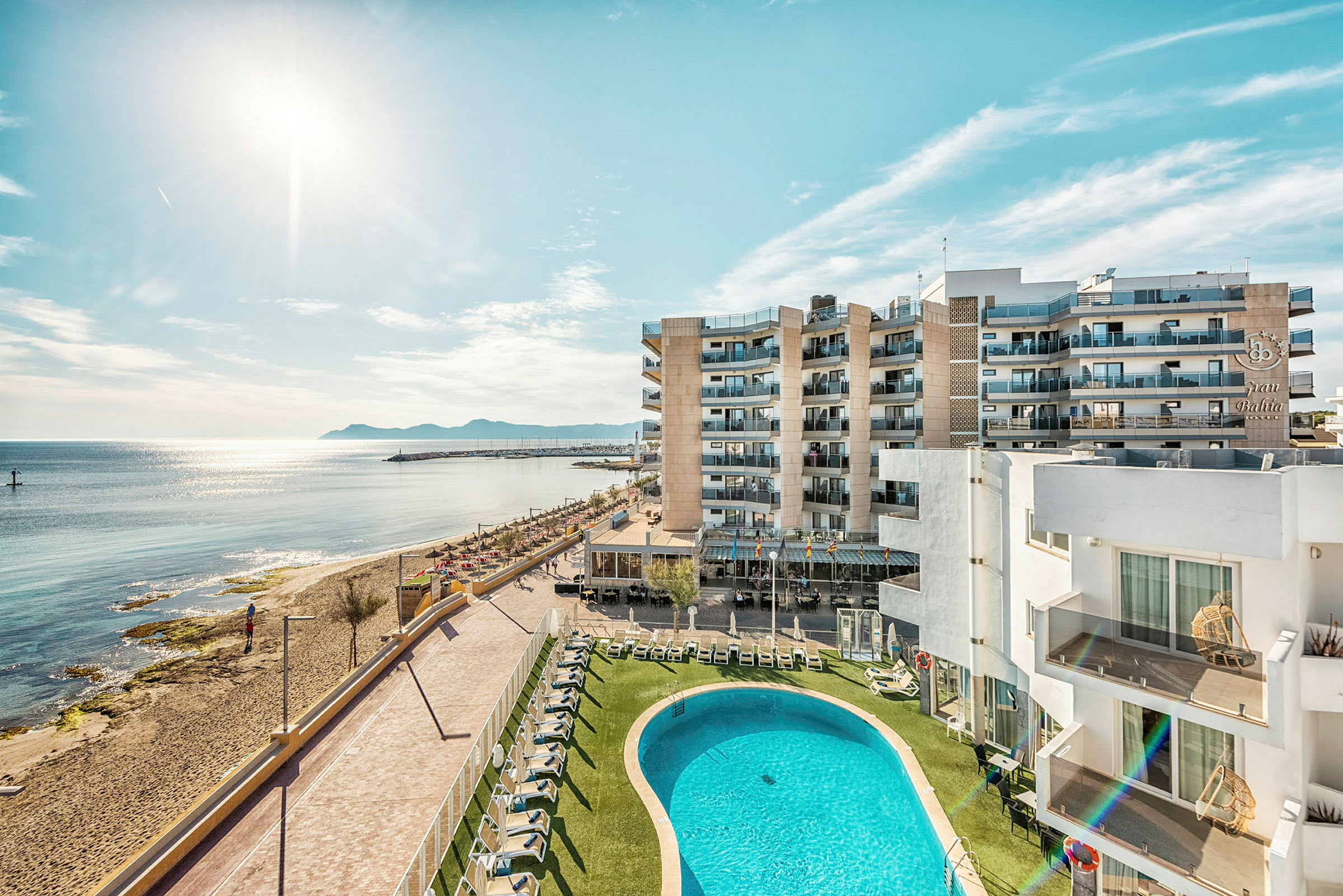 Hotellbyggnader vid stranden med poolområde och hav i bakgrunden. (AI-genererad text)