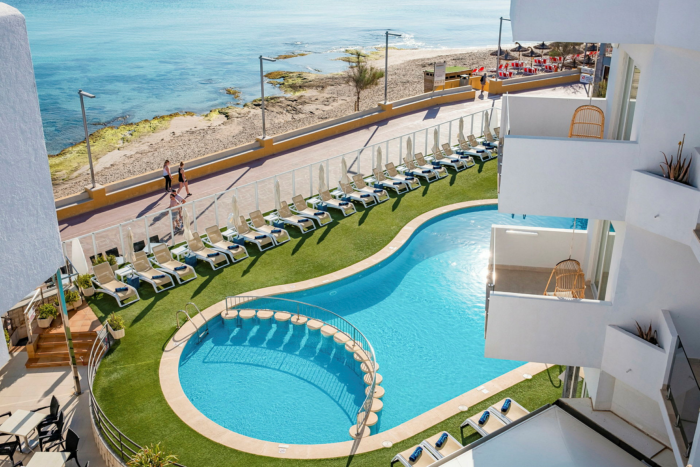 Hotellpool med solstolar och närhet till strand och promenadväg. (AI-genererad text)