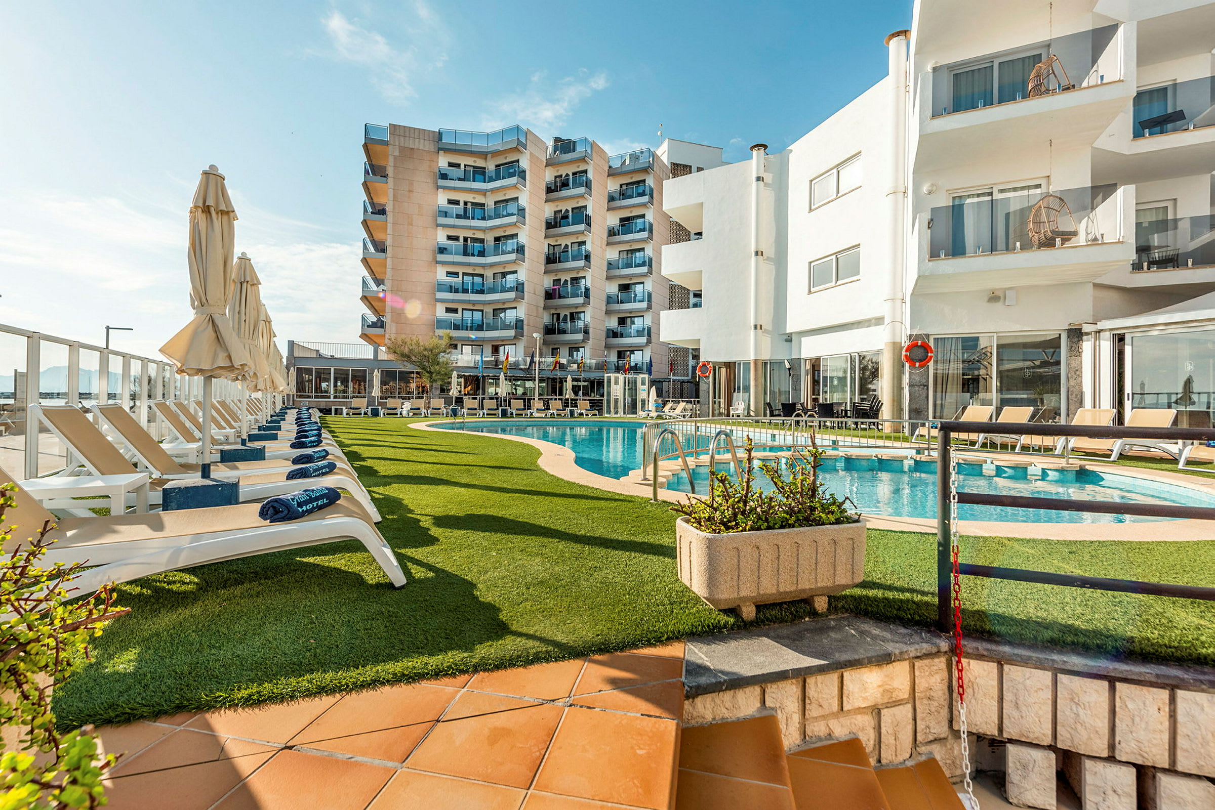 Hotellbyggnad med poolområde och solstolar. (AI-genererad text)