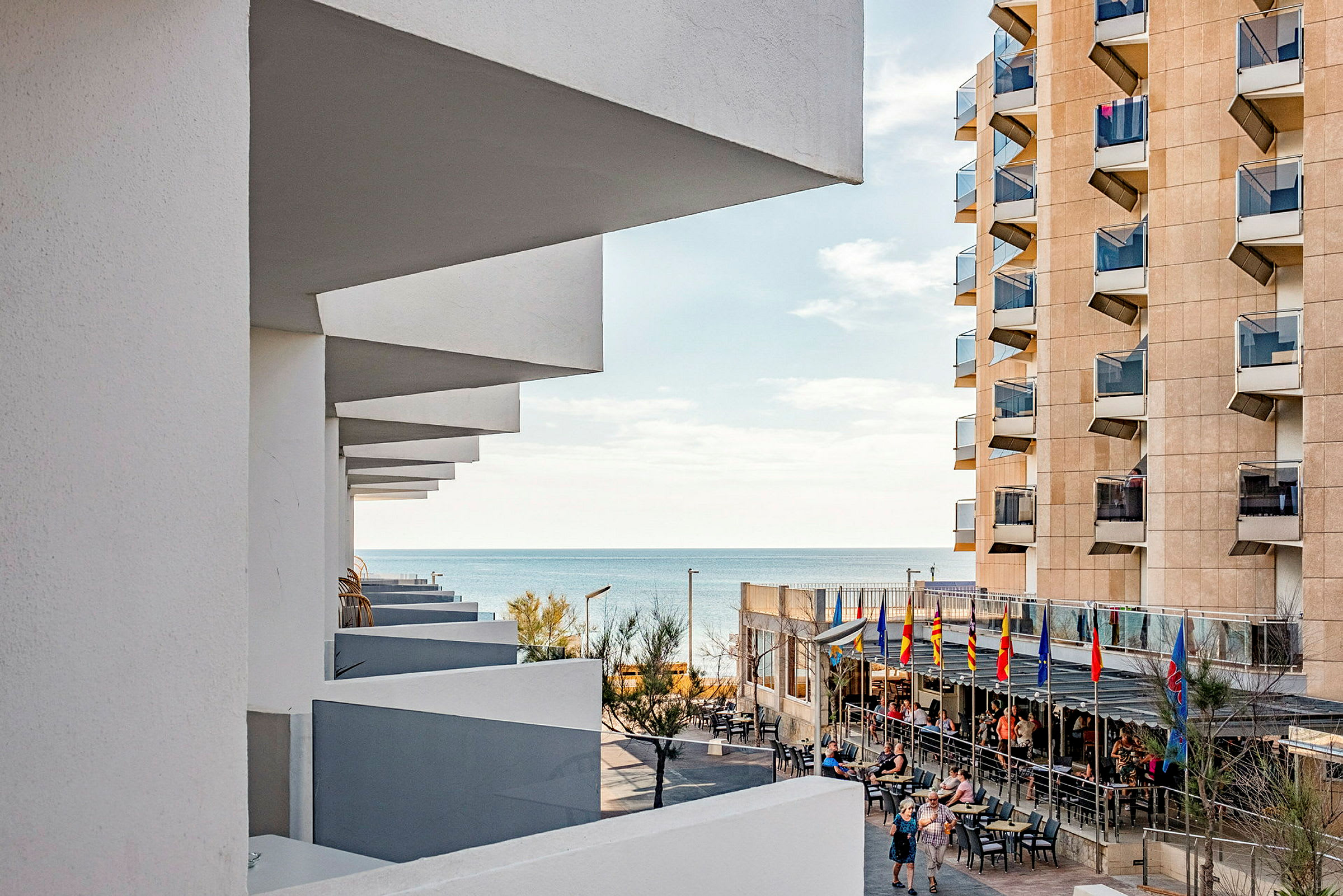 En utsikt av havet sett från ett hotell med terrass och balkonger på byggnaden. (AI-genererad text)