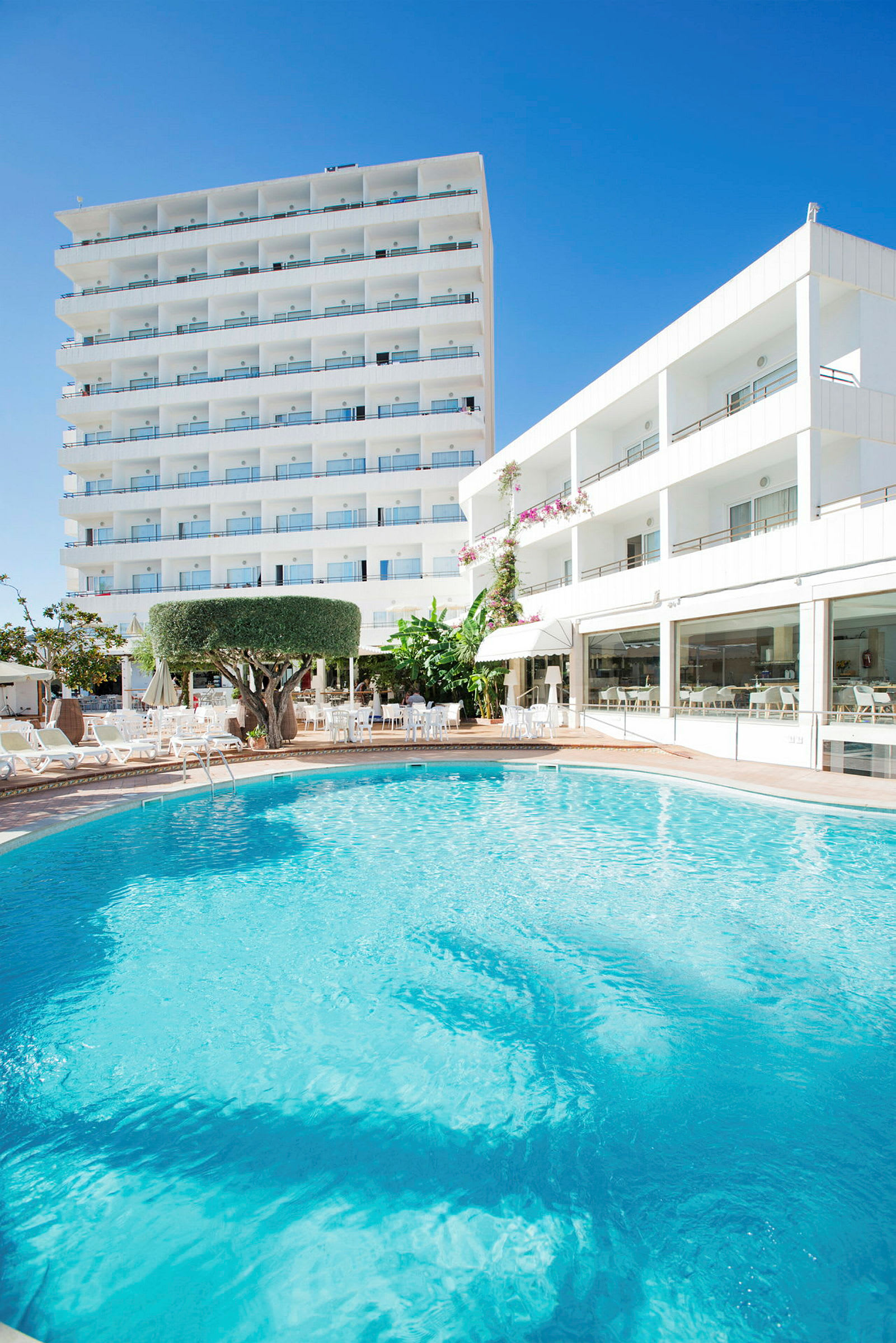 Utomhuspool framför hotellbyggnad. (AI-genererad text)