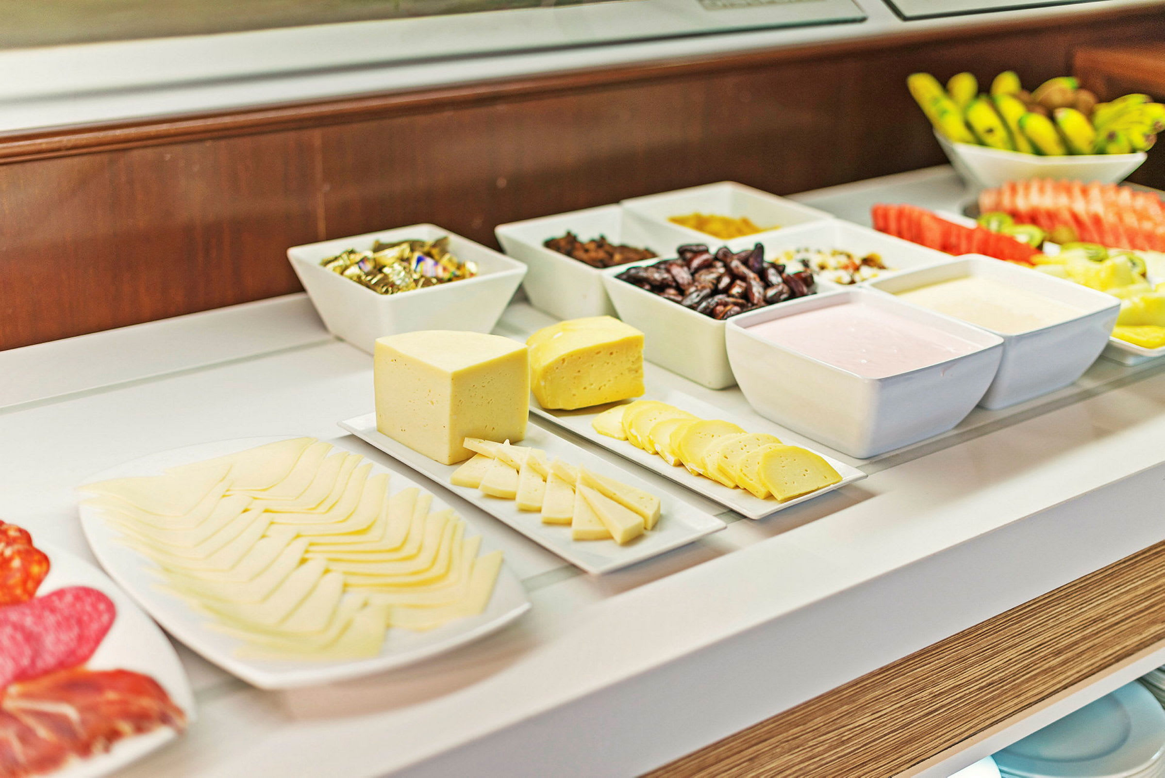 Ett buffébord med olika typer av ost, frukt och tillbehör. Det finns också små skålar med diverse livsmedel. (AI-genererad text)