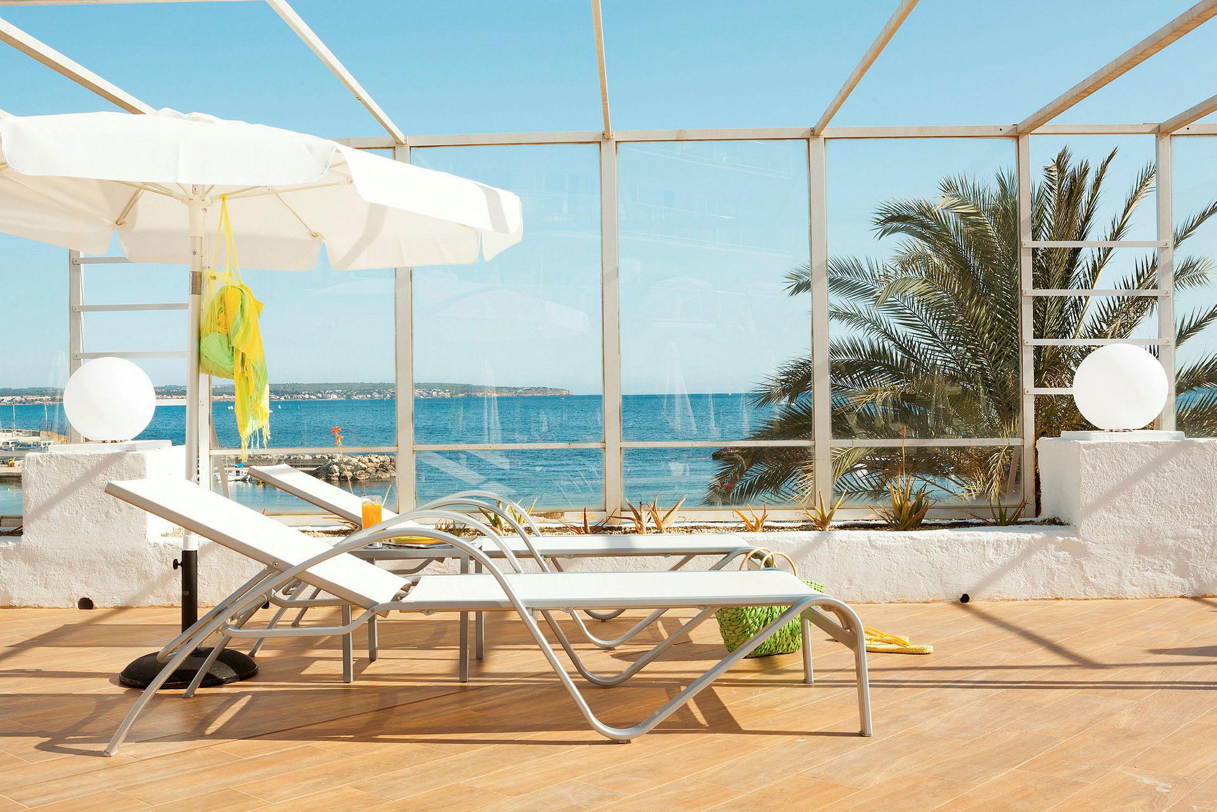 Två solstolar och en vit parasoll på en terrass med utsikt över havet. (AI-genererad text)