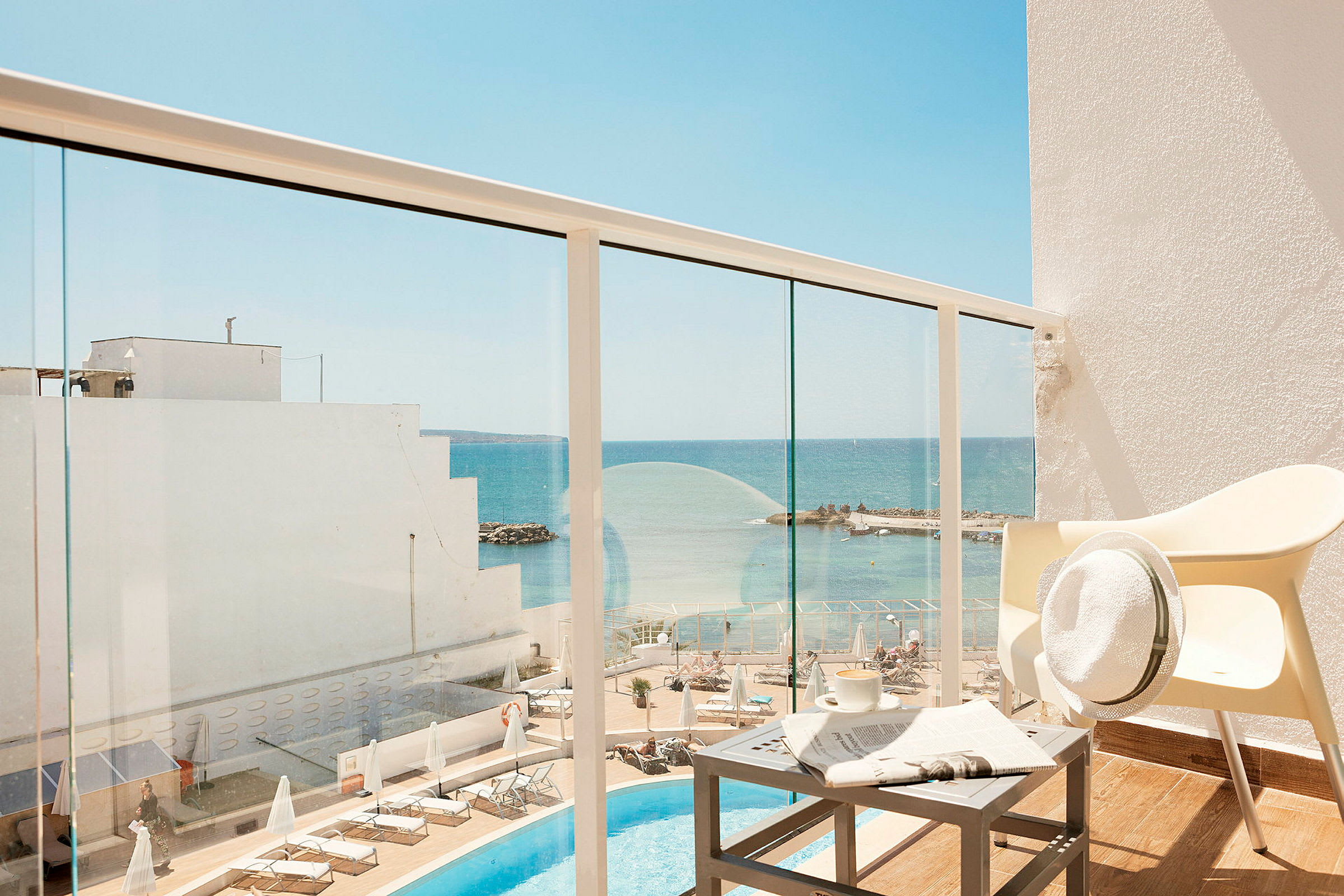 Hotellbalkong med utsikt över poolområde och hav. (AI-genererad text)