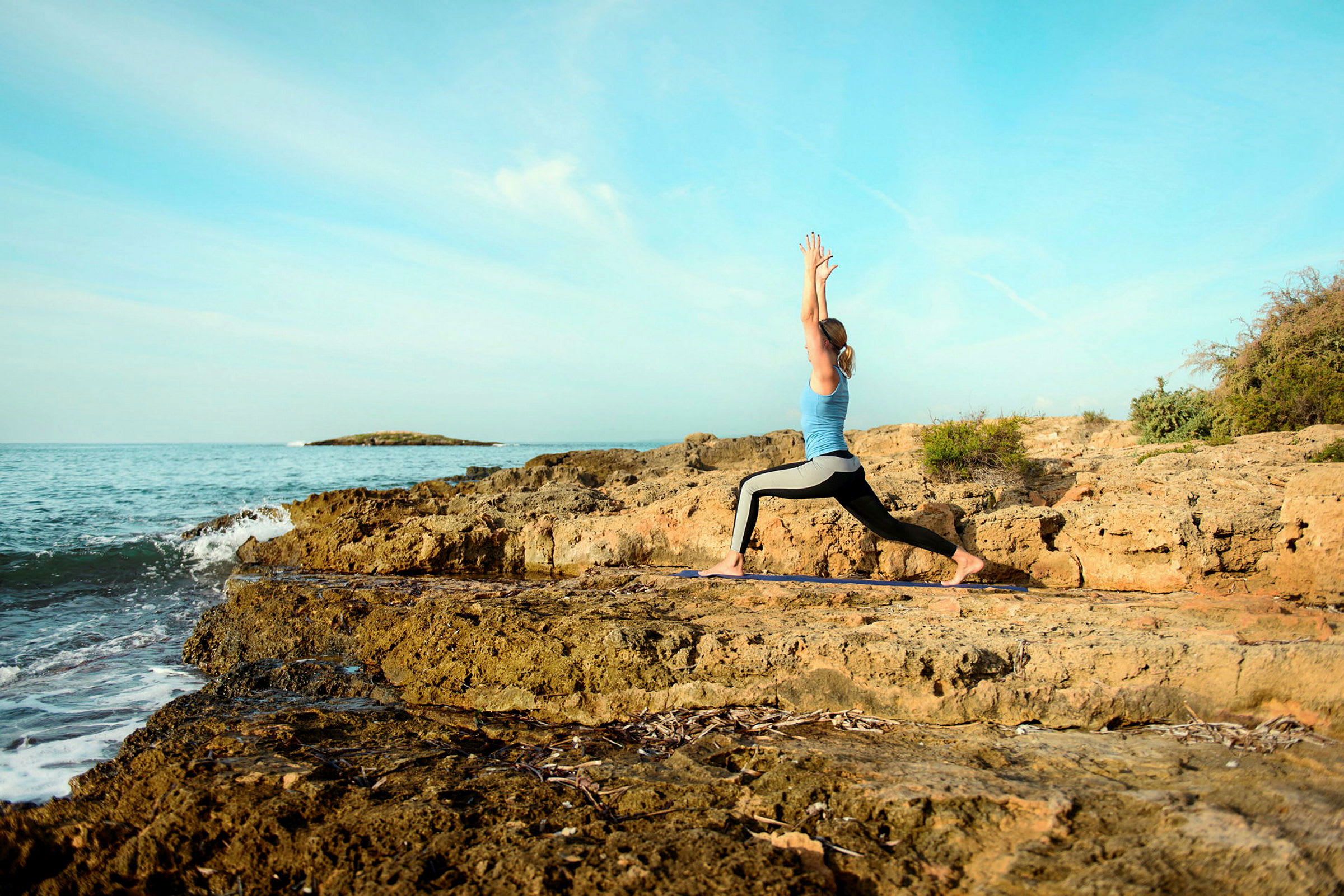 Person utför yogaövning på stenig kust vid havet. (AI-genererad text)